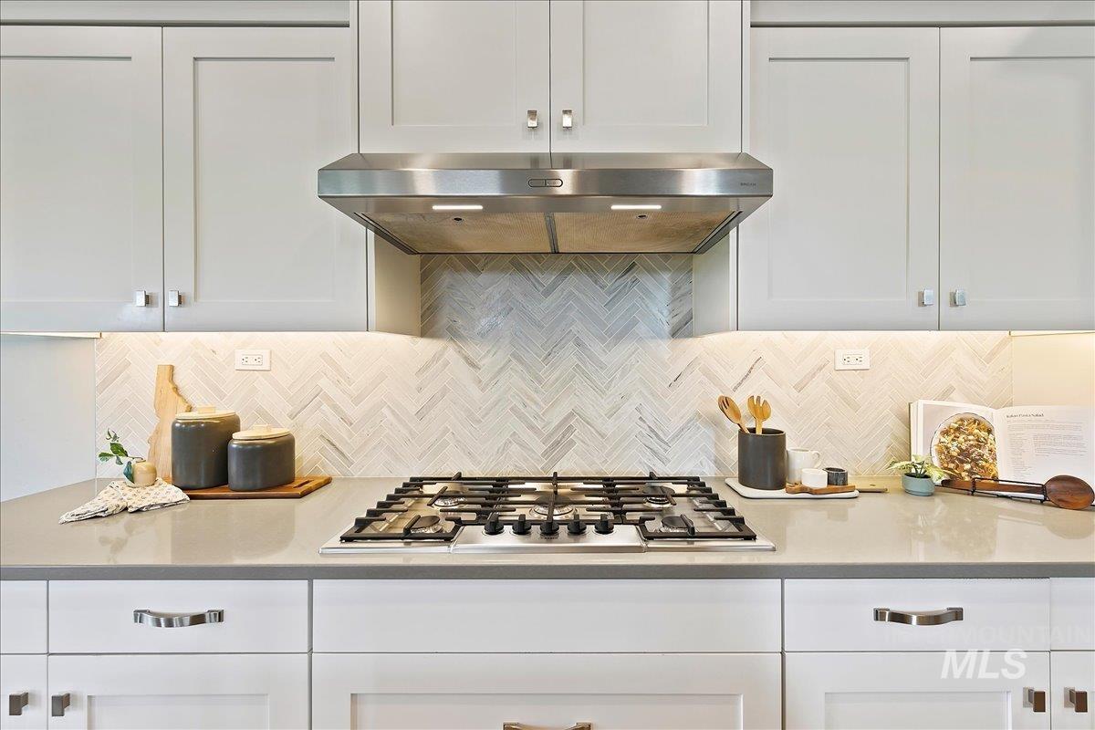 Kitchen featuring backsplash, white cabinetry, and stainless steel gas stovetop