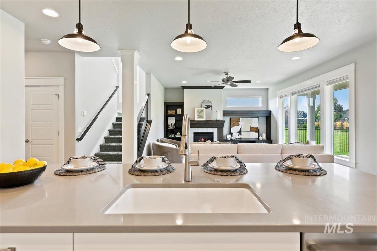 Kitchen with hanging light fixtures, a lit fireplace, open floor plan, recessed lighting, and light stone countertops