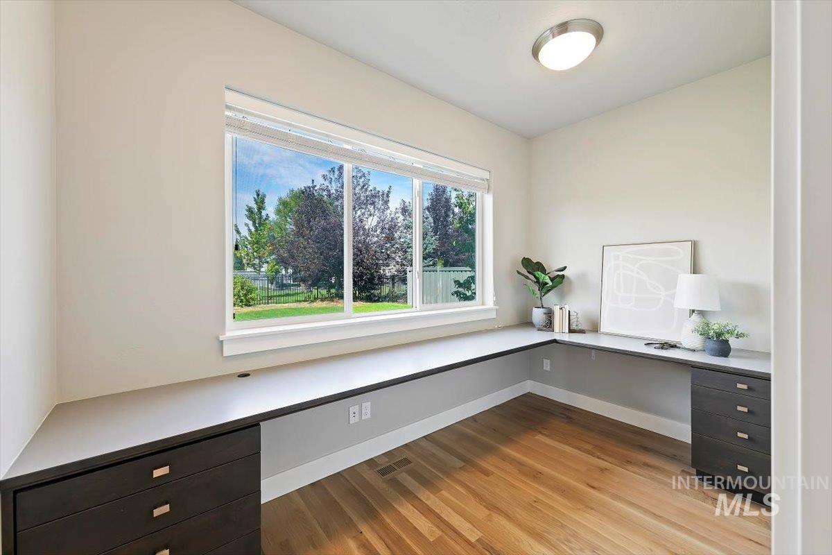Unfurnished office with built in desk and light wood finished floors
