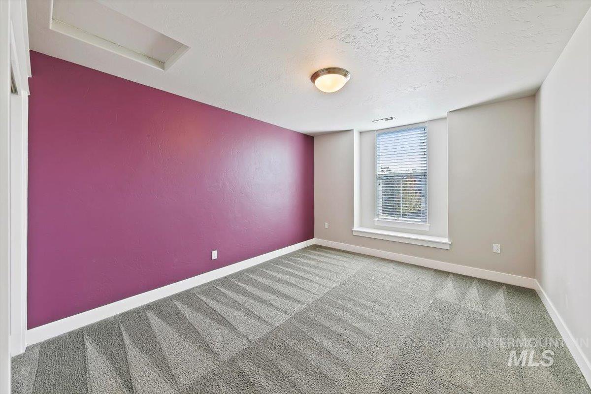 Spare room featuring carpet flooring, a textured ceiling, and attic access