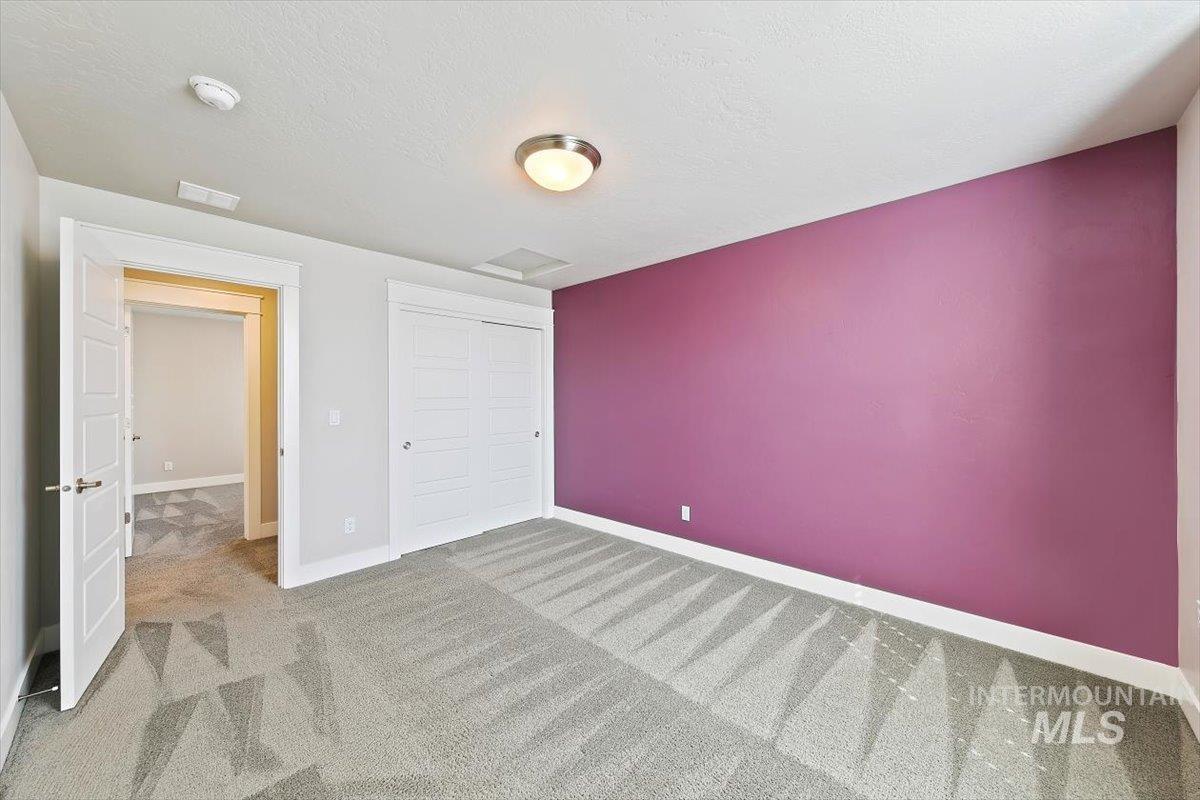 Unfurnished bedroom featuring carpet flooring, a textured ceiling, and a closet