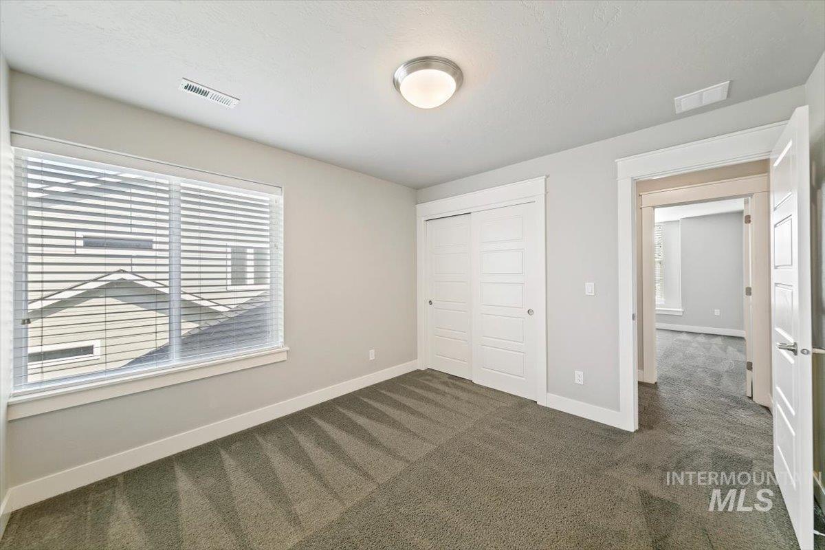 Unfurnished bedroom featuring dark colored carpet and a closet