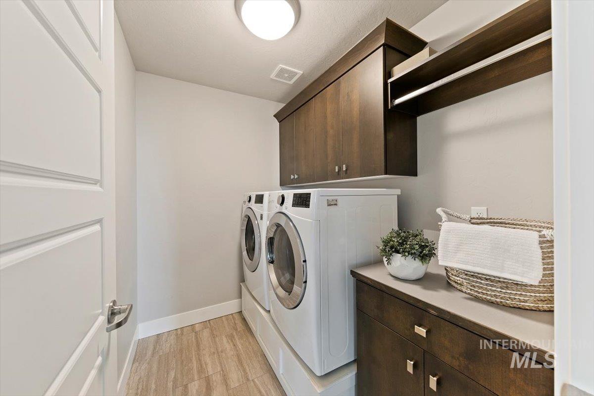 Laundry area with cabinet space, washing machine and dryer, and light wood-style flooring