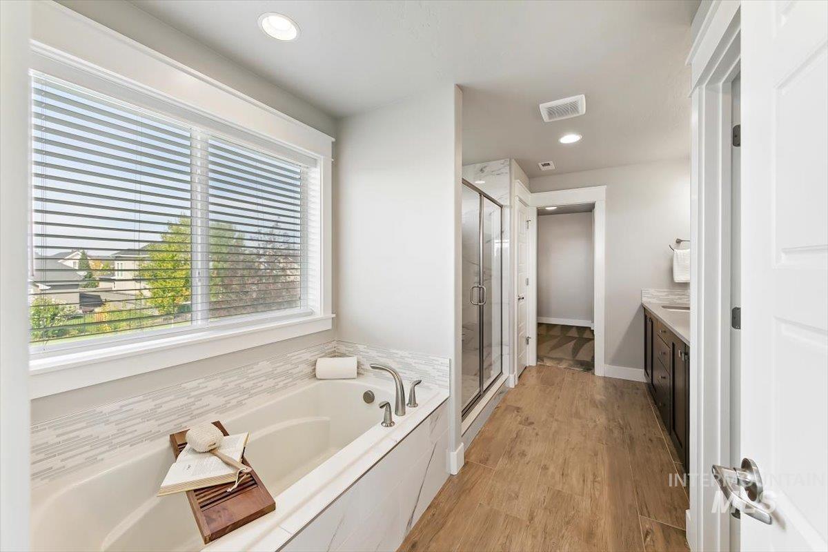 Full bath featuring vanity, a bath, light wood-type flooring, a stall shower, and recessed lighting