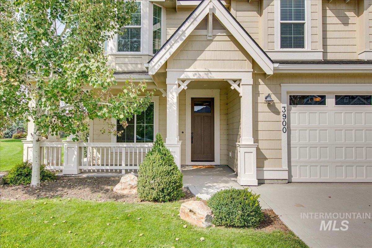 View of exterior entry featuring a yard, covered porch, and an attached garage
