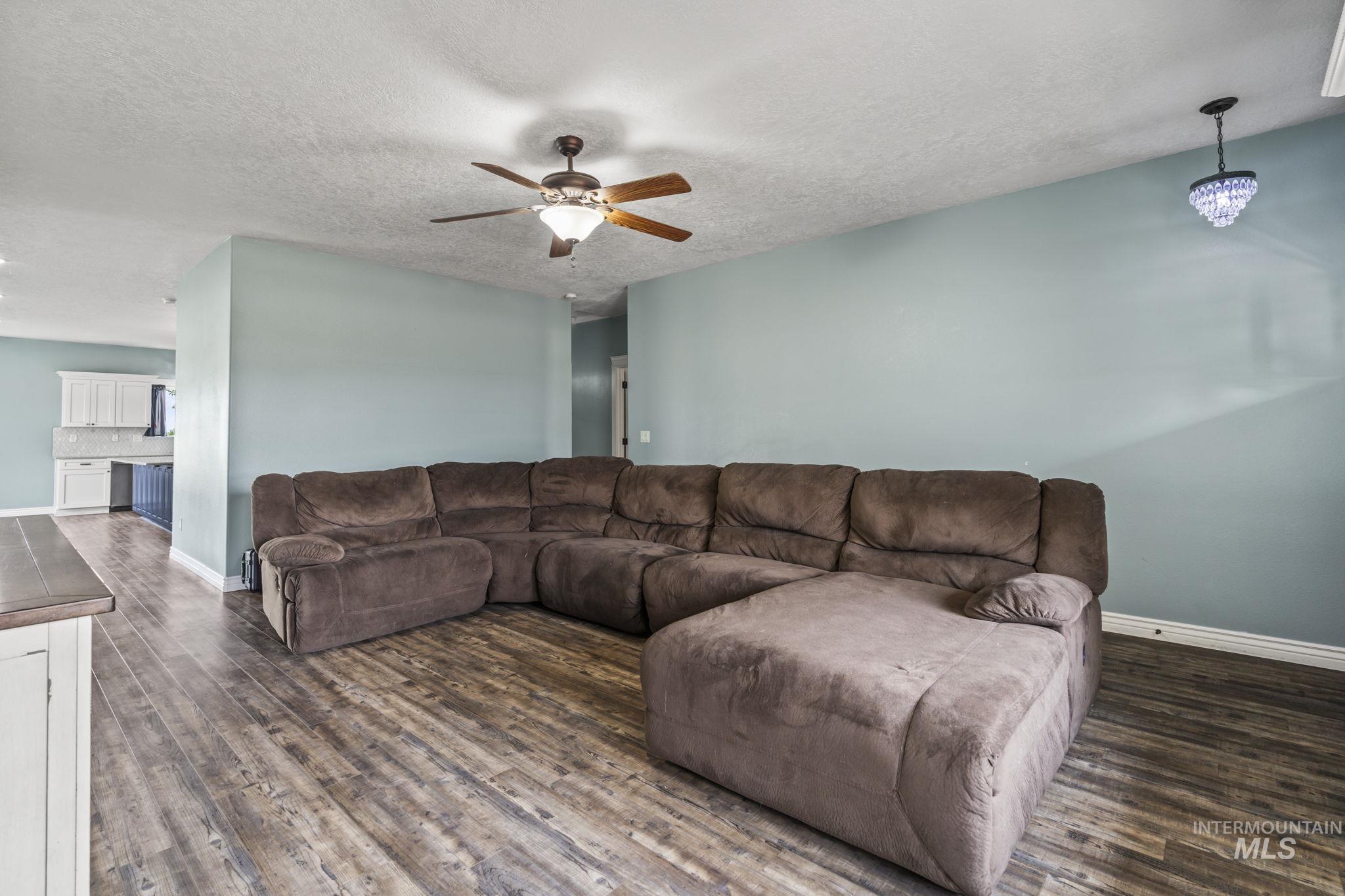 Living area featuring dark wood-style flooring, ceiling fan, and a textured ceiling