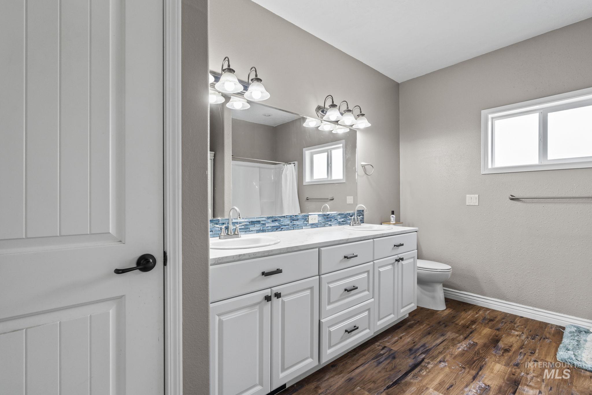 Bathroom featuring double vanity, dark wood-type flooring, and a shower with curtain