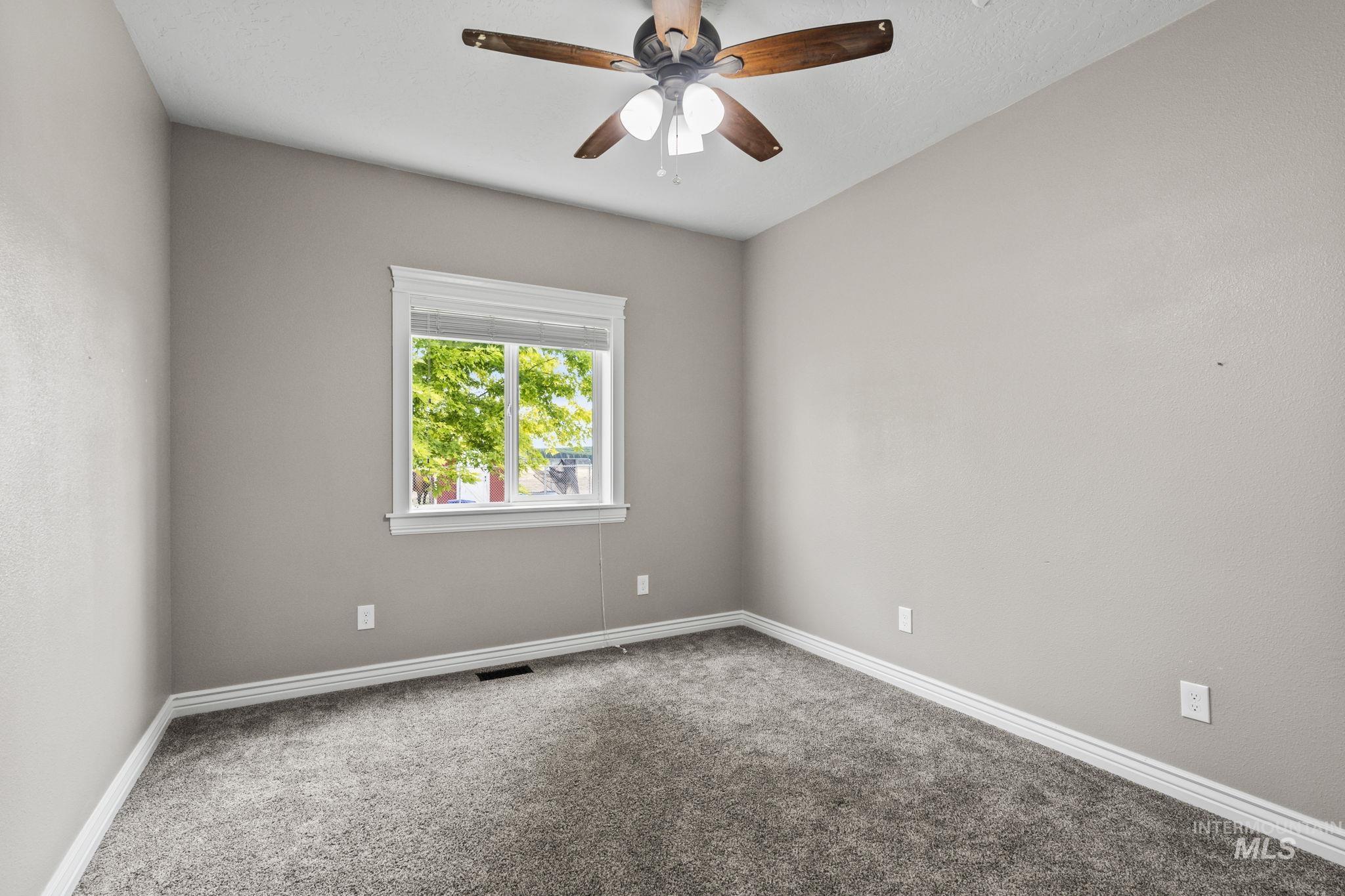 Carpeted empty room featuring baseboards and a ceiling fan