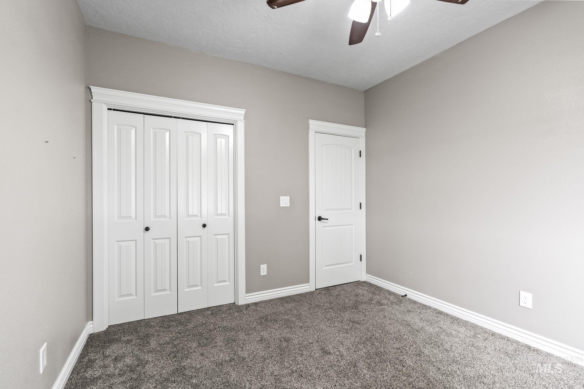 Unfurnished bedroom featuring carpet flooring, a closet, a textured ceiling, and ceiling fan
