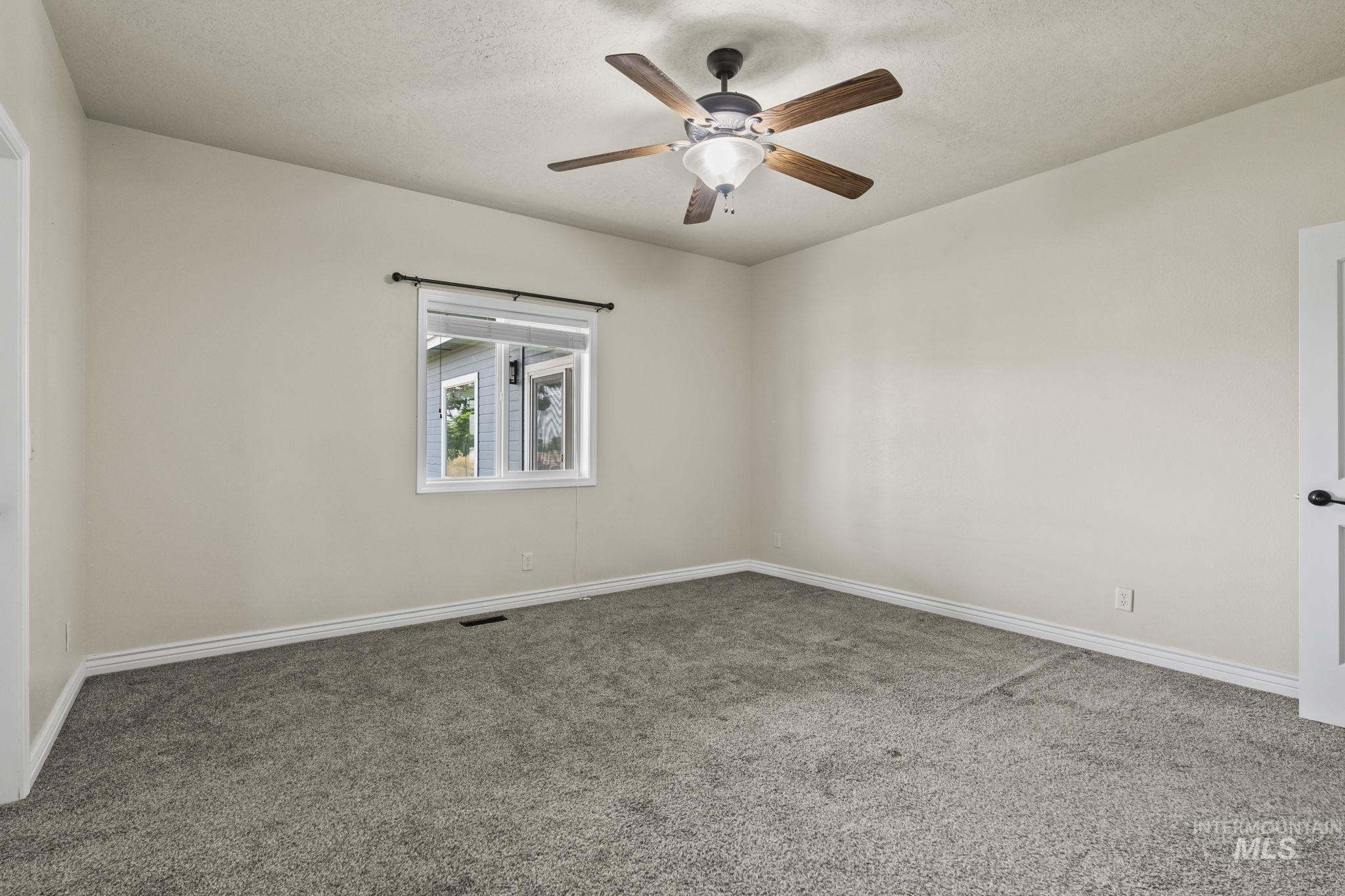 Spare room featuring carpet, a textured ceiling, and ceiling fan