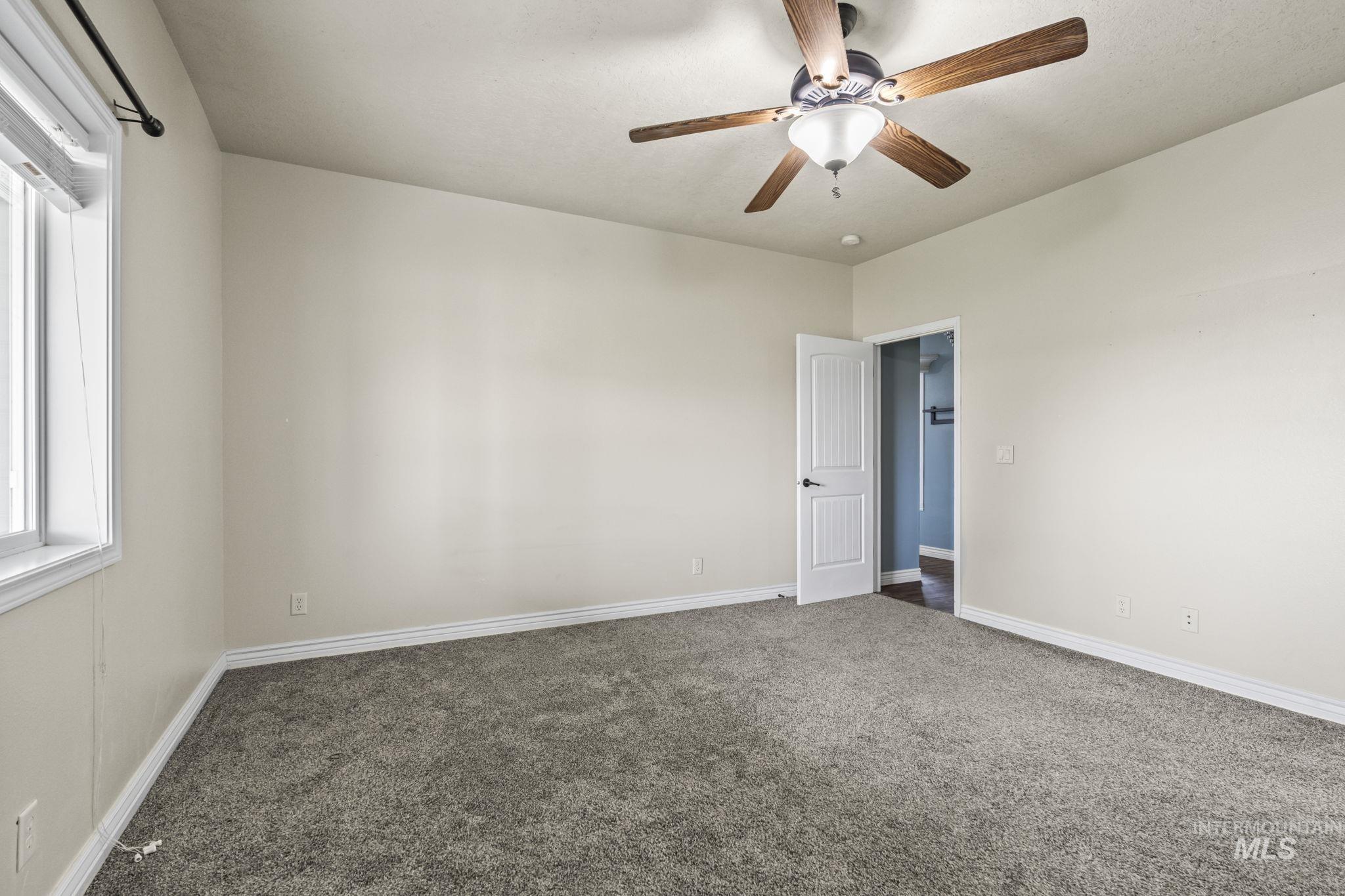 Unfurnished room featuring healthy amount of natural light, carpet, and a ceiling fan