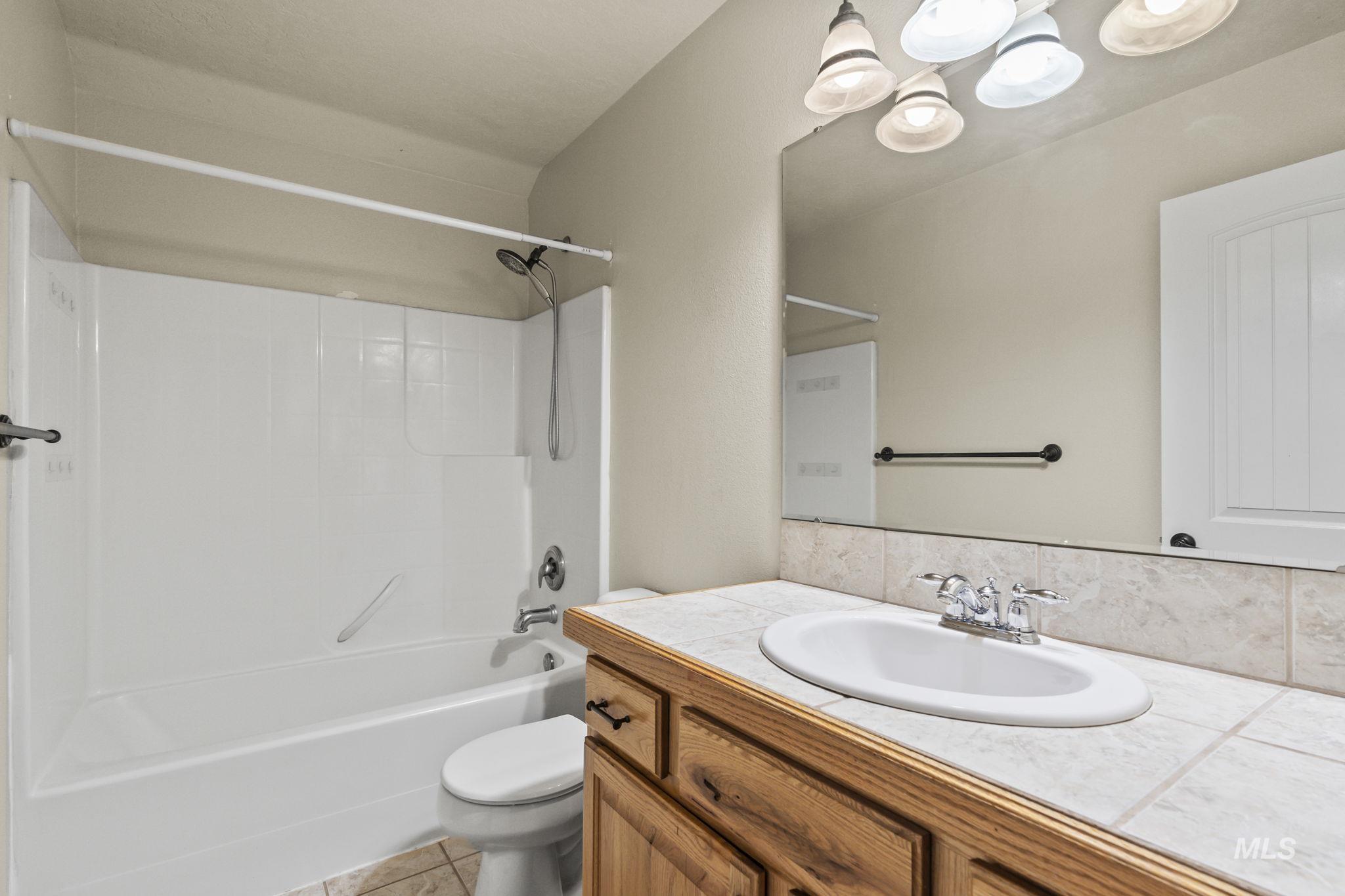 Bathroom featuring tub / shower combination, vanity, light tile patterned flooring, and a chandelier