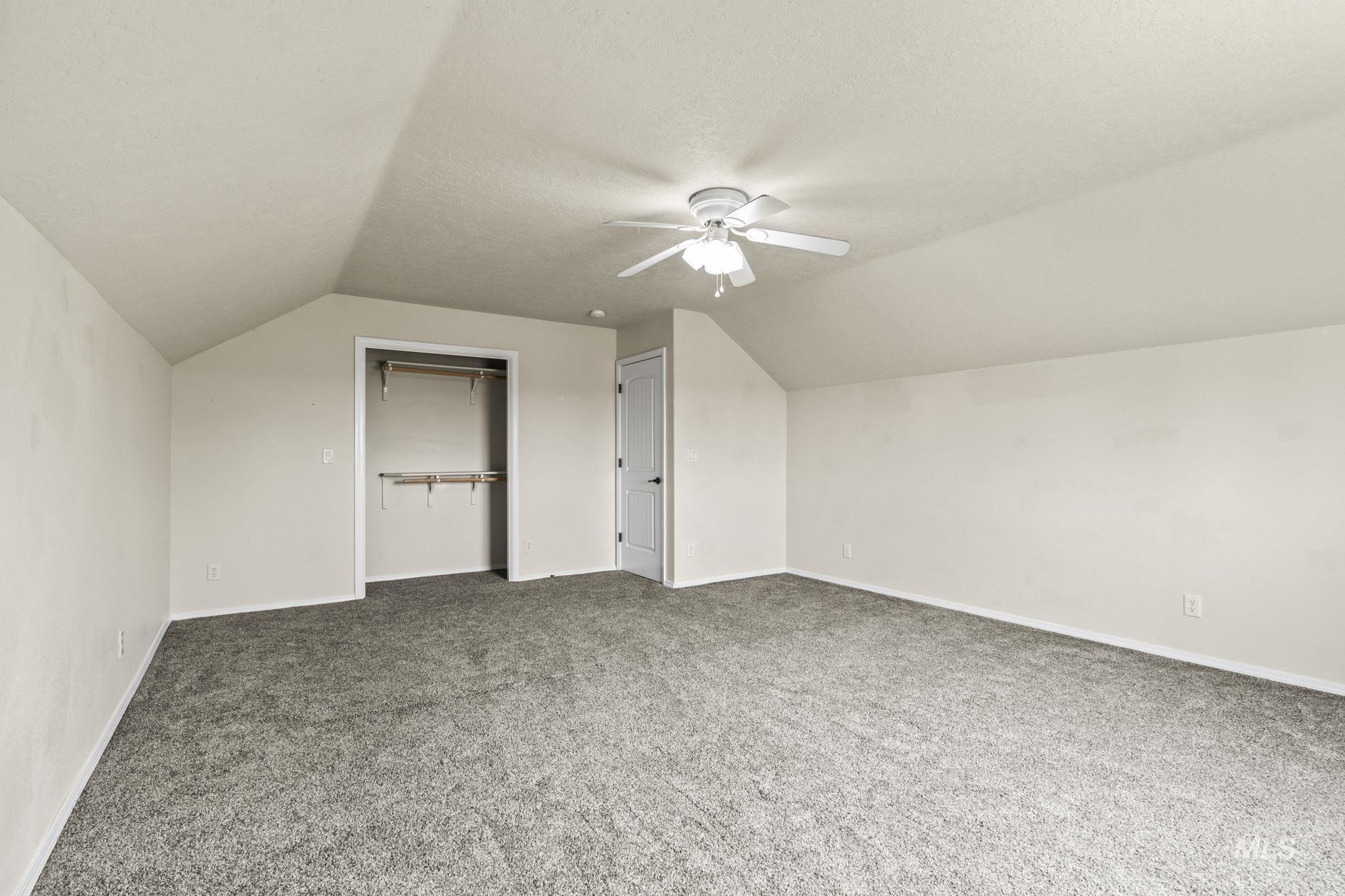 Additional living space with lofted ceiling, light colored carpet, a textured ceiling, and a ceiling fan