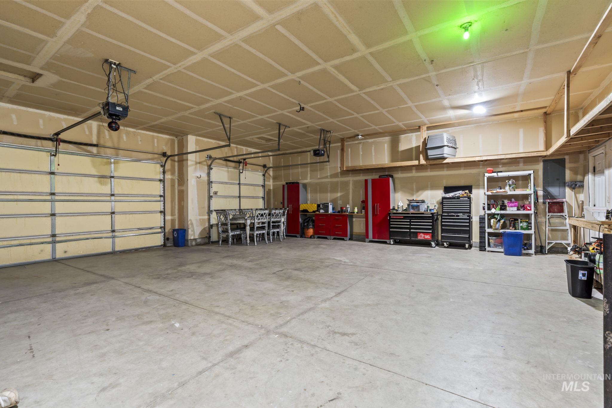 Garage featuring electric panel, a heating unit, and a garage door opener