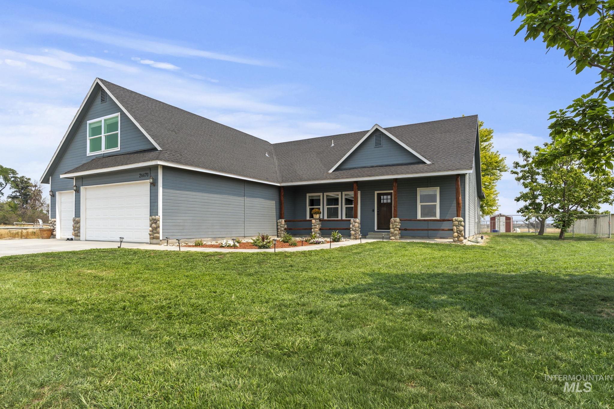 View of front facade with roof with shingles, covered porch, a front lawn, and driveway