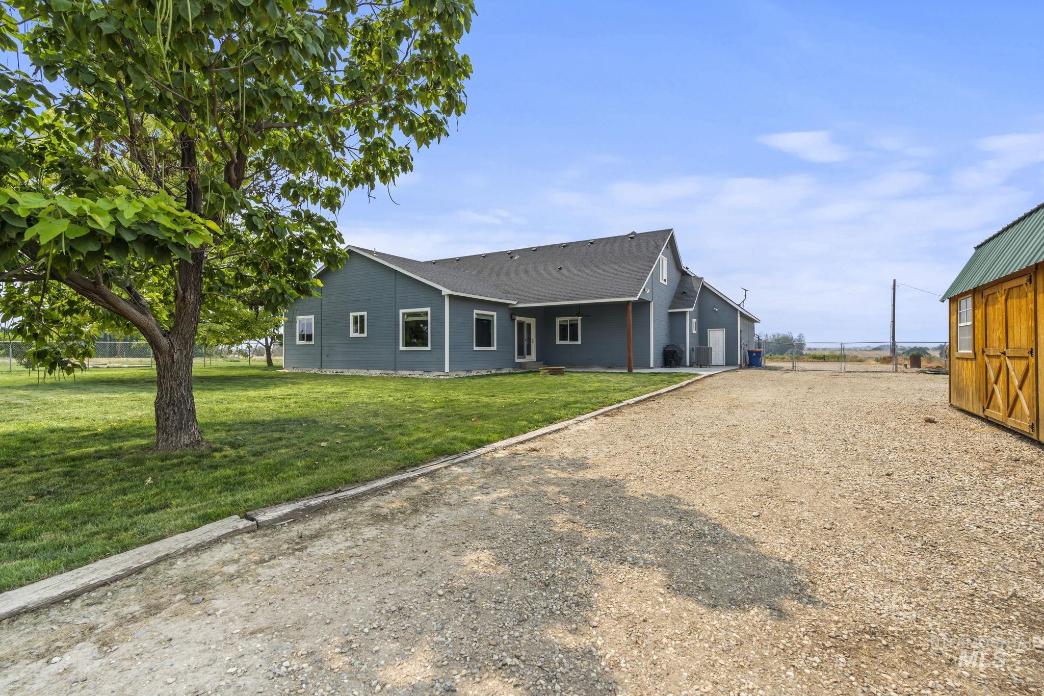 View of front of house featuring driveway, a patio area, a shingled roof, and an attached garage
