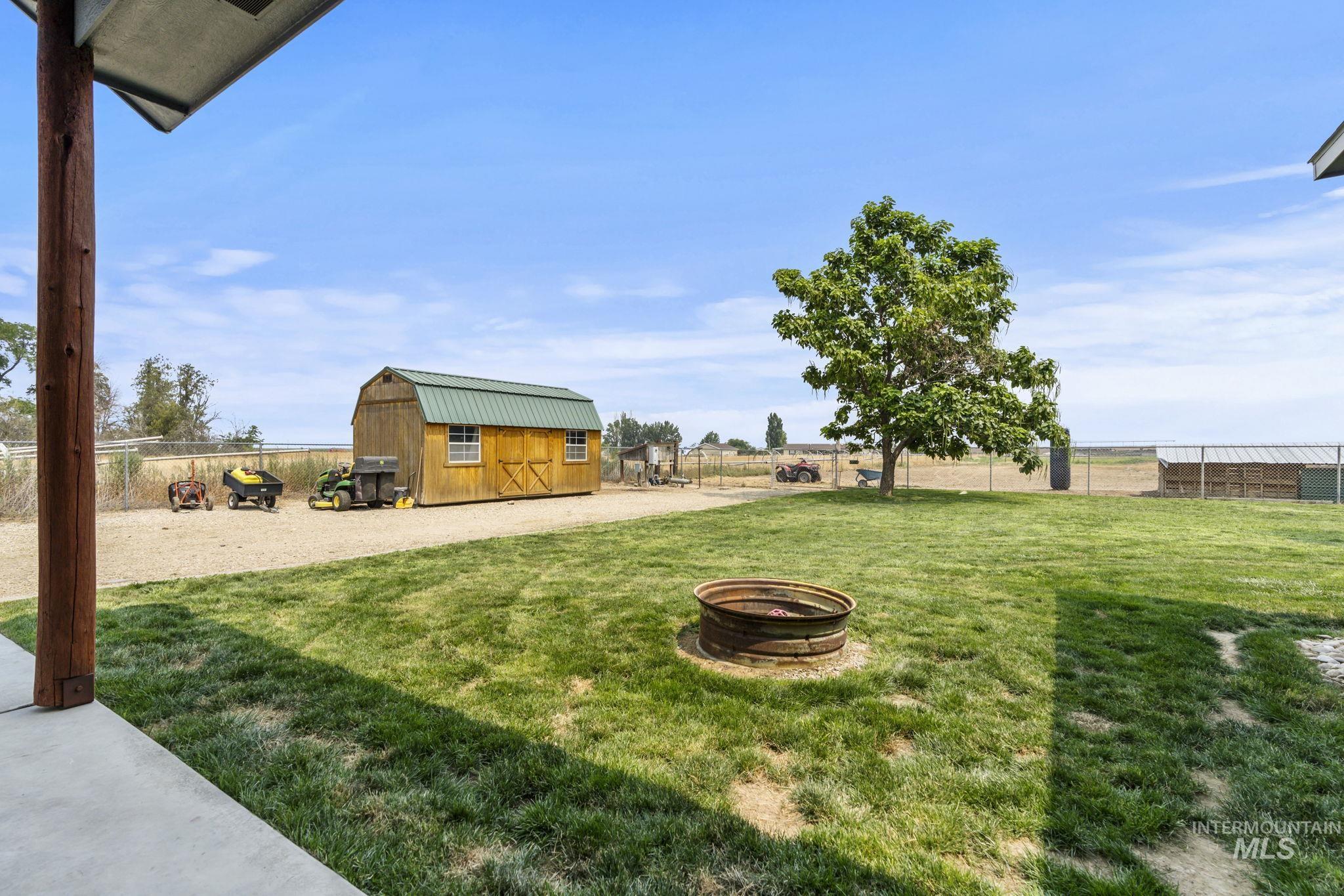 Fenced backyard with a fire pit and a storage unit