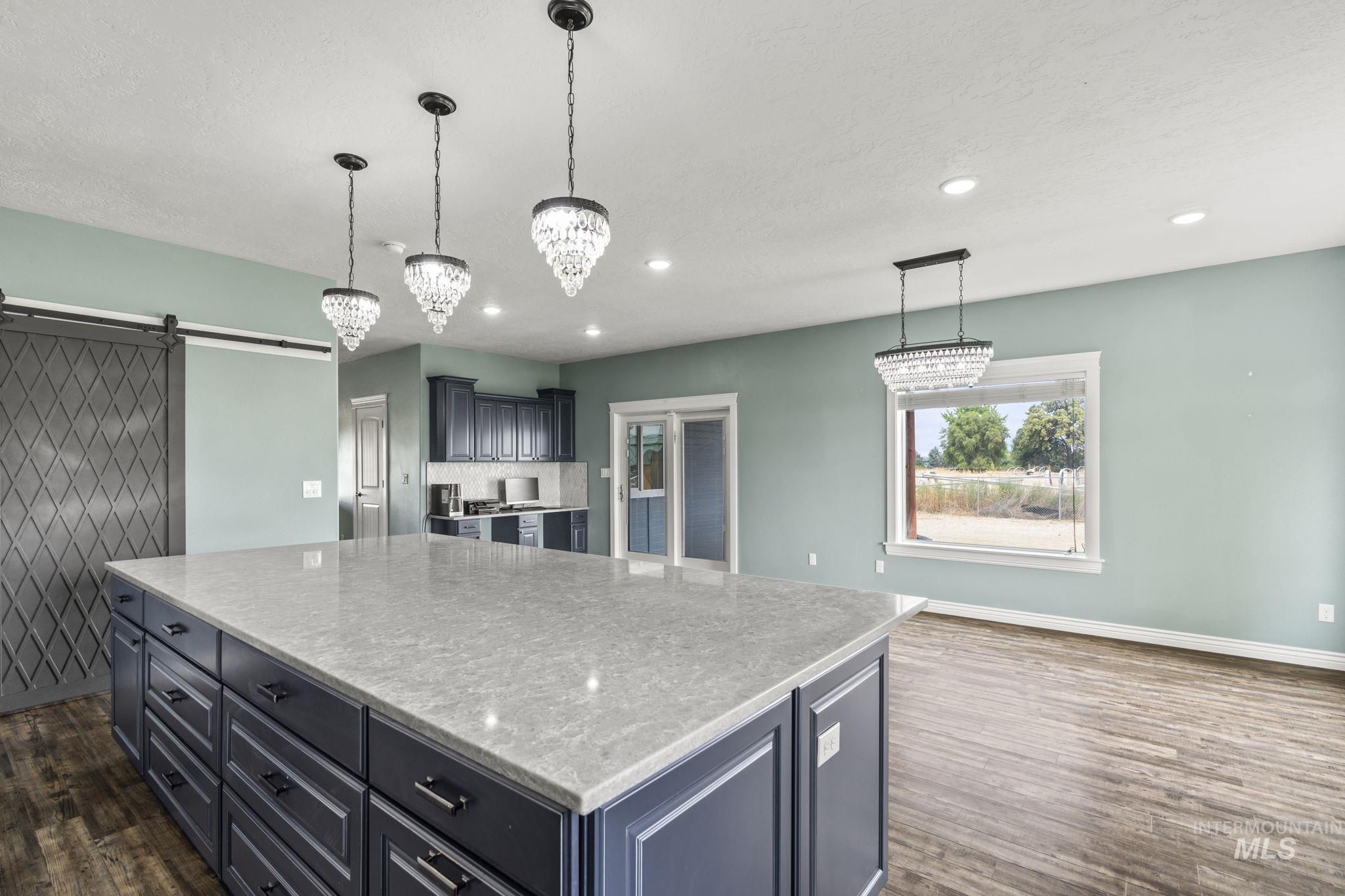 Kitchen with a barn door, a center island, decorative light fixtures, recessed lighting, and dark wood-style floors