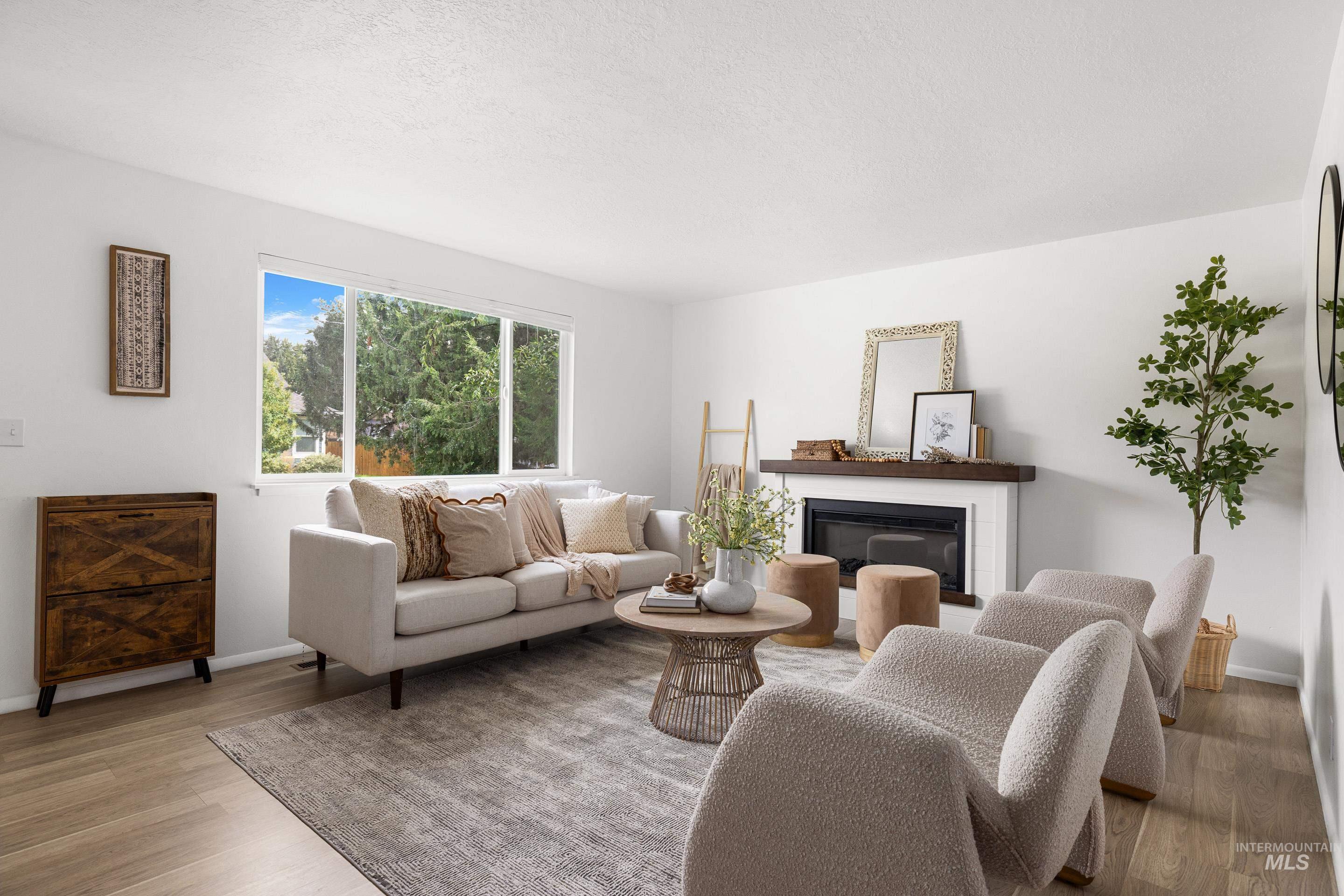 Living room featuring light wood-style floors, a glass covered fireplace, and a textured ceiling