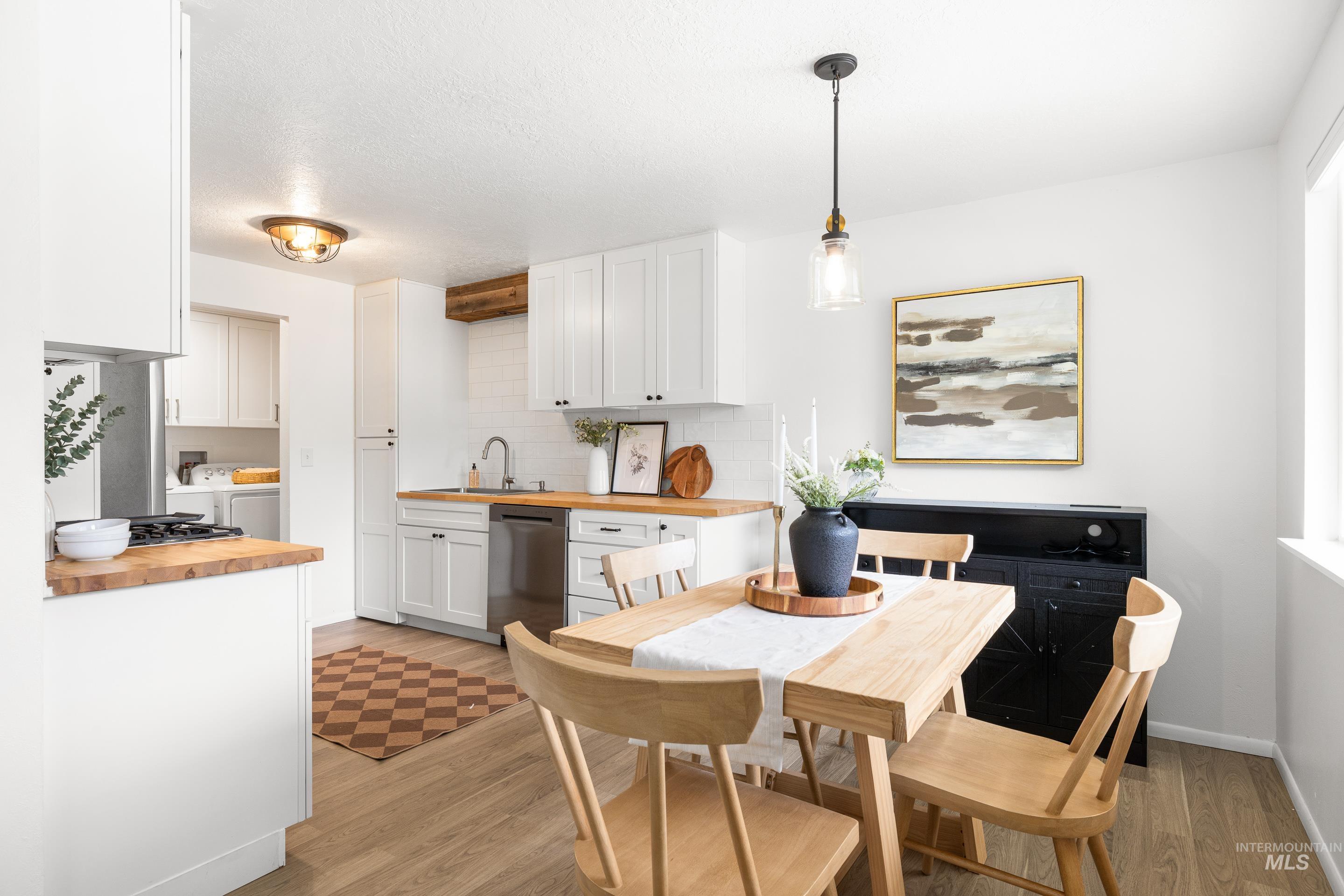 Dining area featuring light wood finished floors, washing machine and dryer, and a textured ceiling