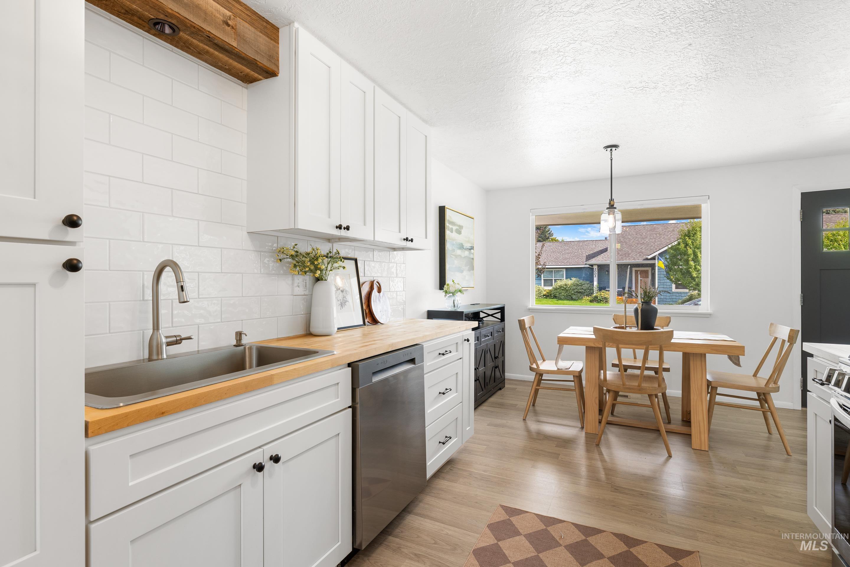 Kitchen featuring white cabinetry, tasteful backsplash, butcher block countertops, light wood-type flooring, and a textured ceiling