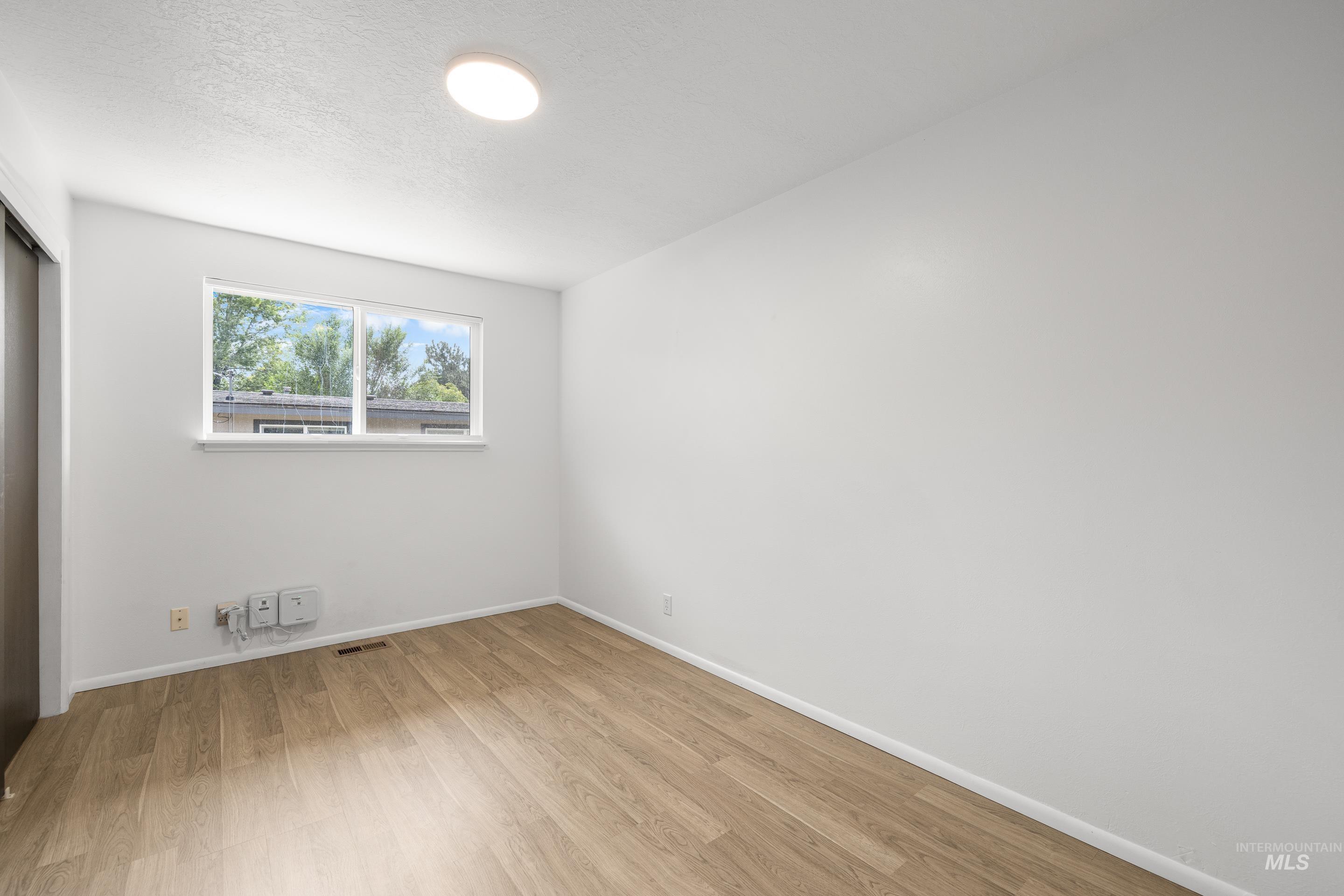 Unfurnished bedroom featuring a closet, light wood-style flooring, and a textured ceiling