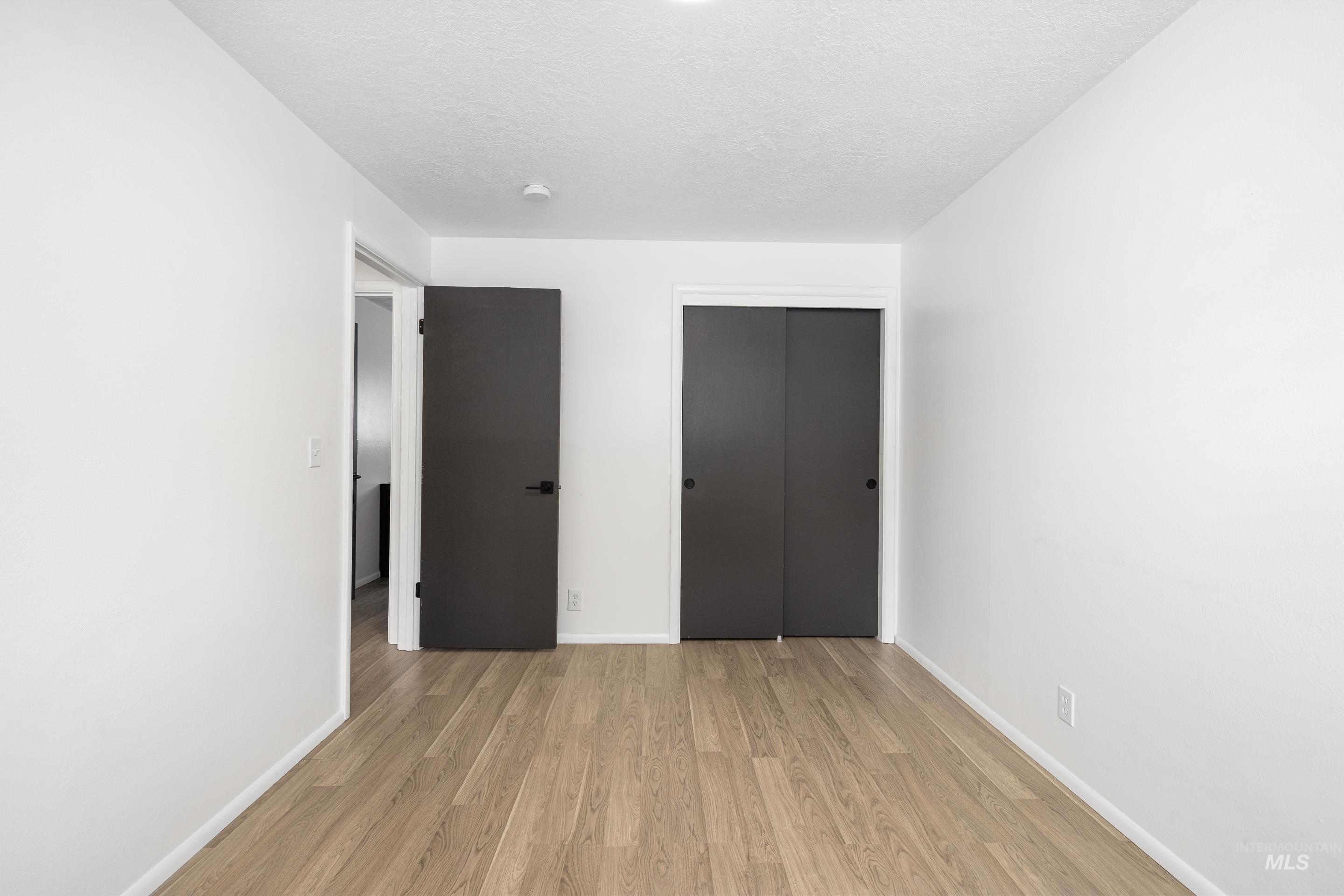 Unfurnished bedroom featuring light wood finished floors, a closet, and a textured ceiling