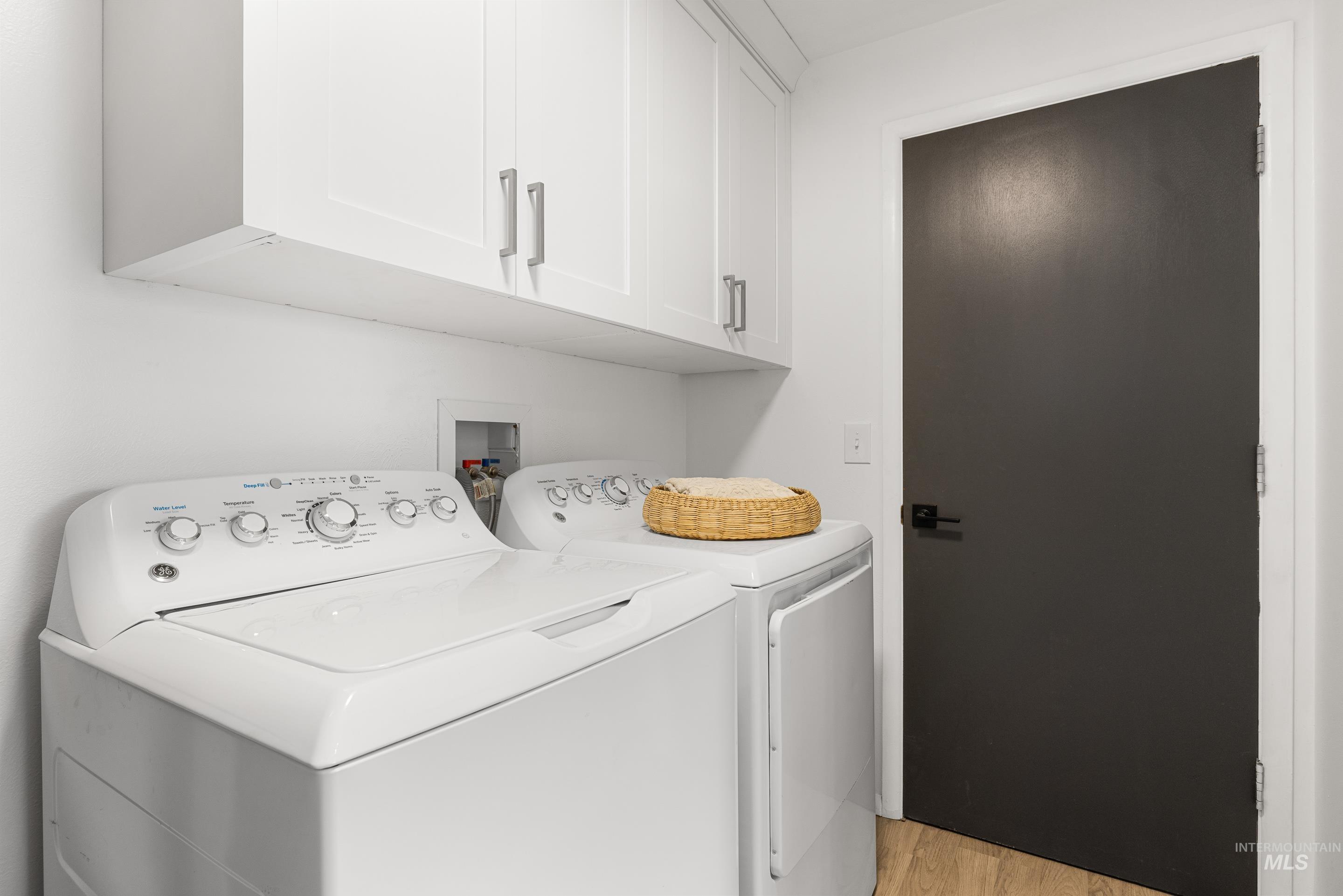 Laundry room with cabinet space, light wood-style floors, and washer and clothes dryer