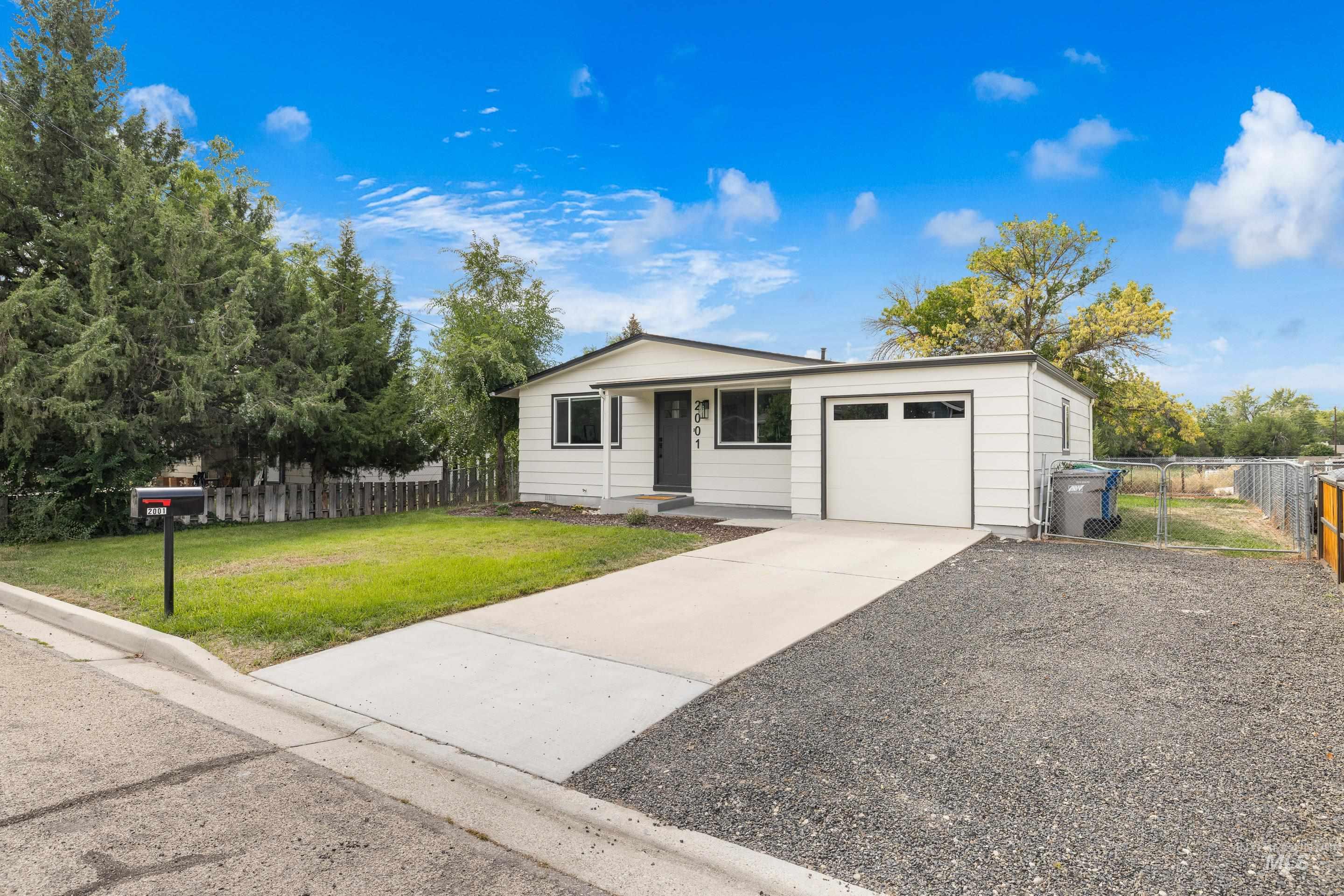 View of front facade featuring driveway, a gate, and an attached garage