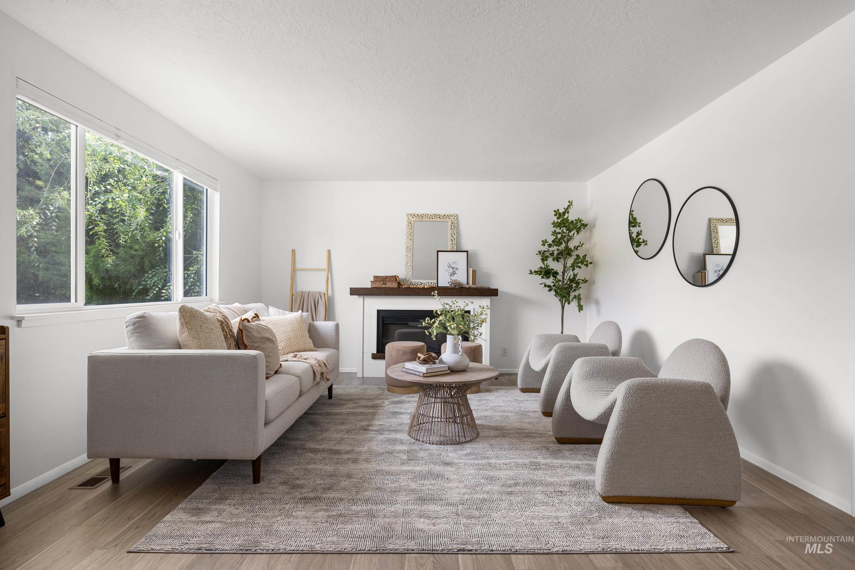 Living room with a glass covered fireplace, light wood-type flooring, and a textured ceiling
