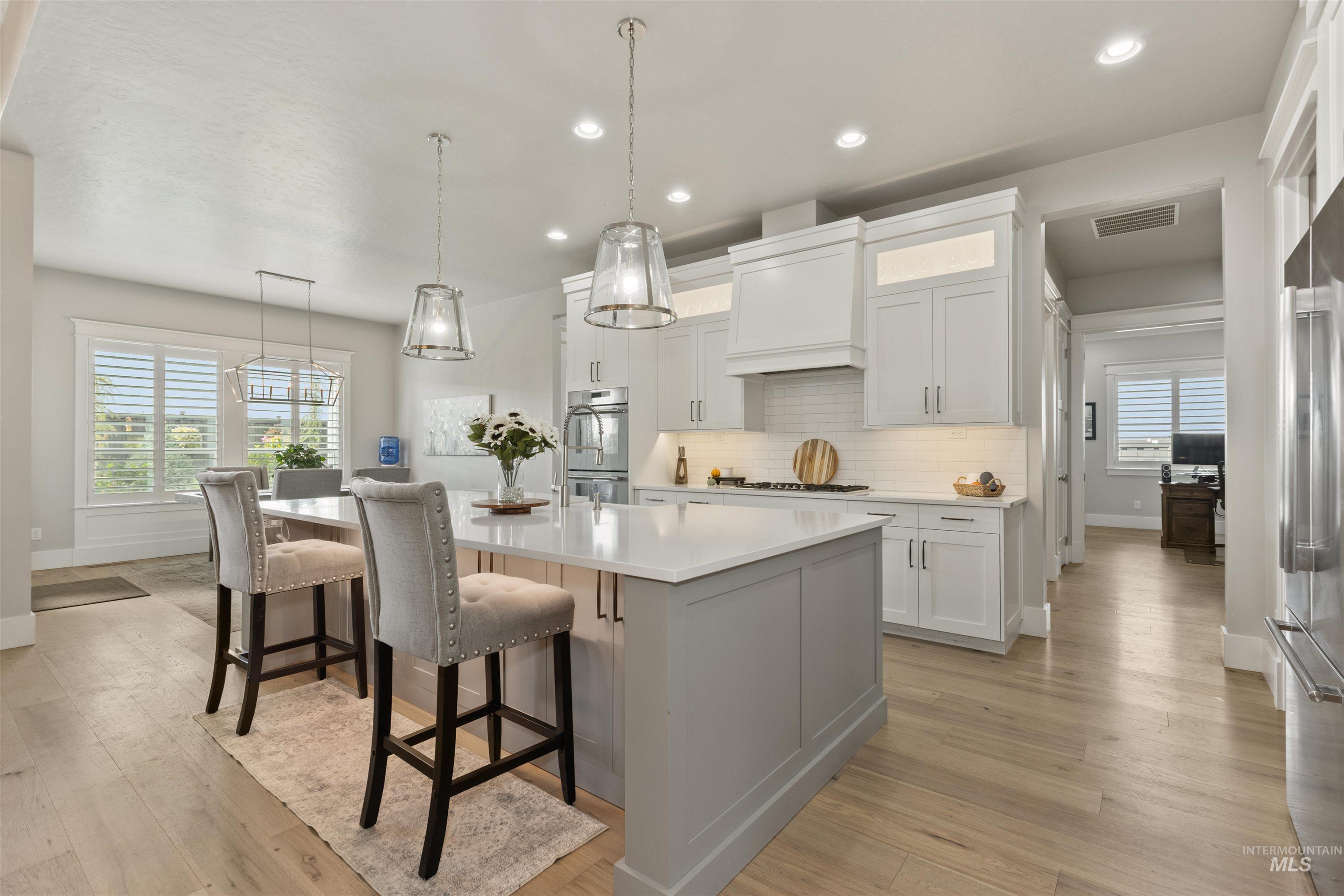 Kitchen with pendant lighting, white cabinets, decorative backsplash, a center island with sink, and recessed lighting