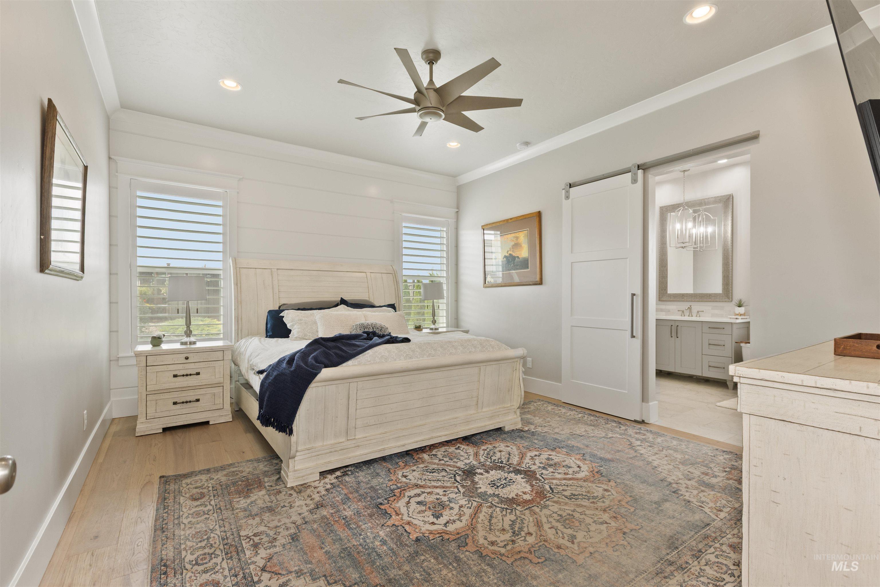 Bedroom featuring a barn door, ornamental molding, light wood finished floors, a ceiling fan, and recessed lighting