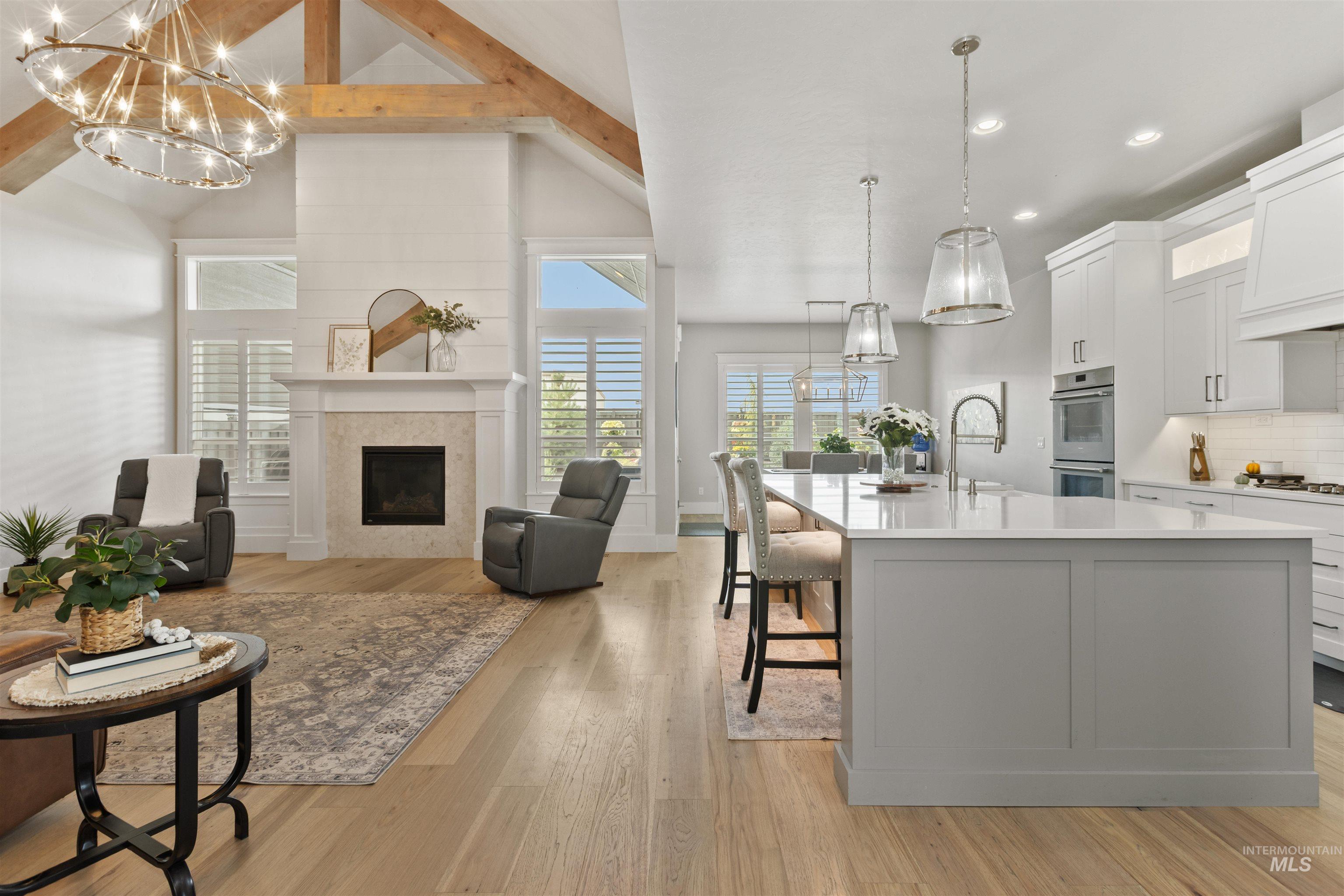 Kitchen with white cabinets, pendant lighting, a chandelier, beamed ceiling, and a kitchen island with sink