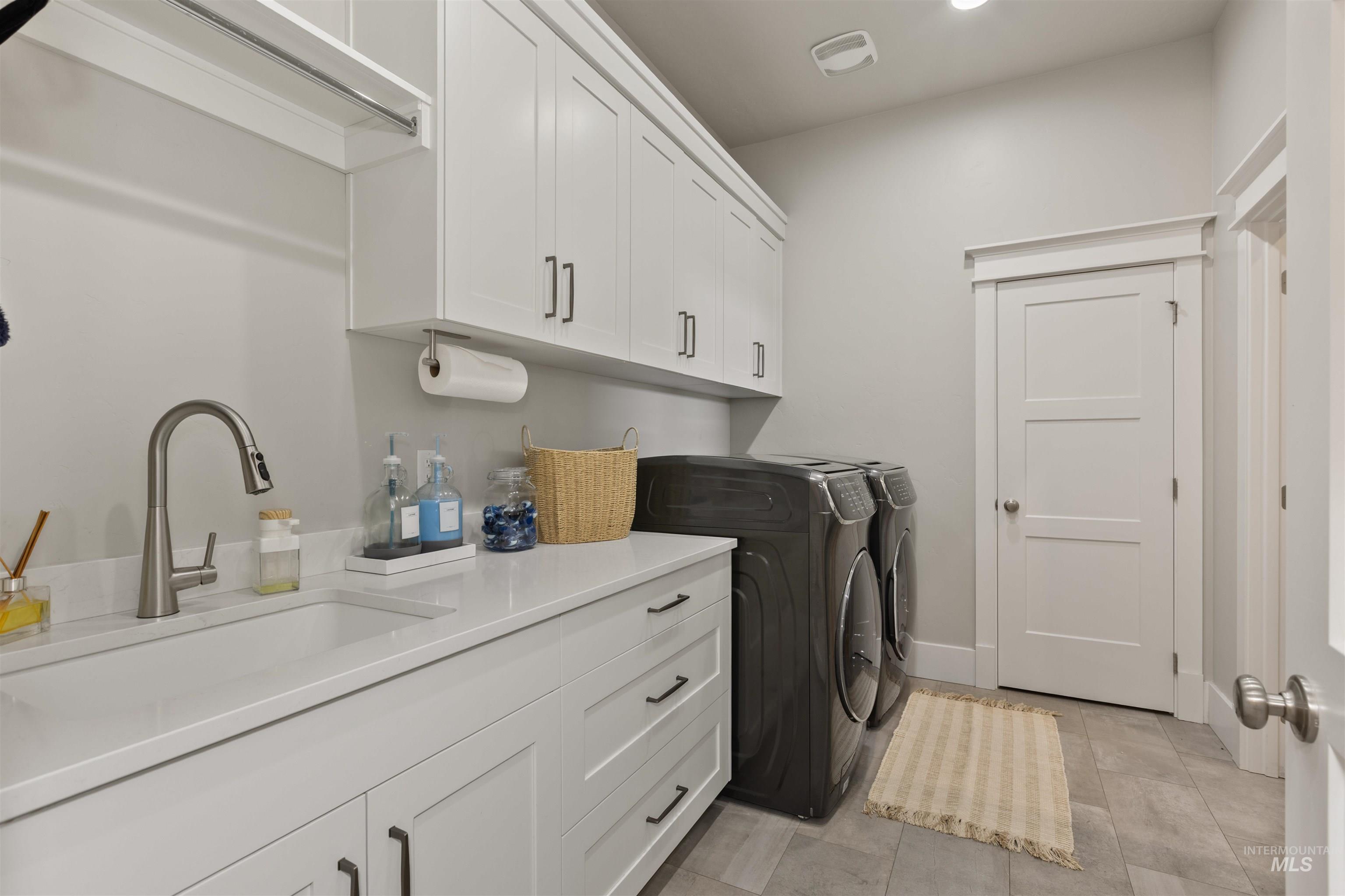Laundry room with washing machine and dryer, cabinet space, light tile patterned floors, and recessed lighting