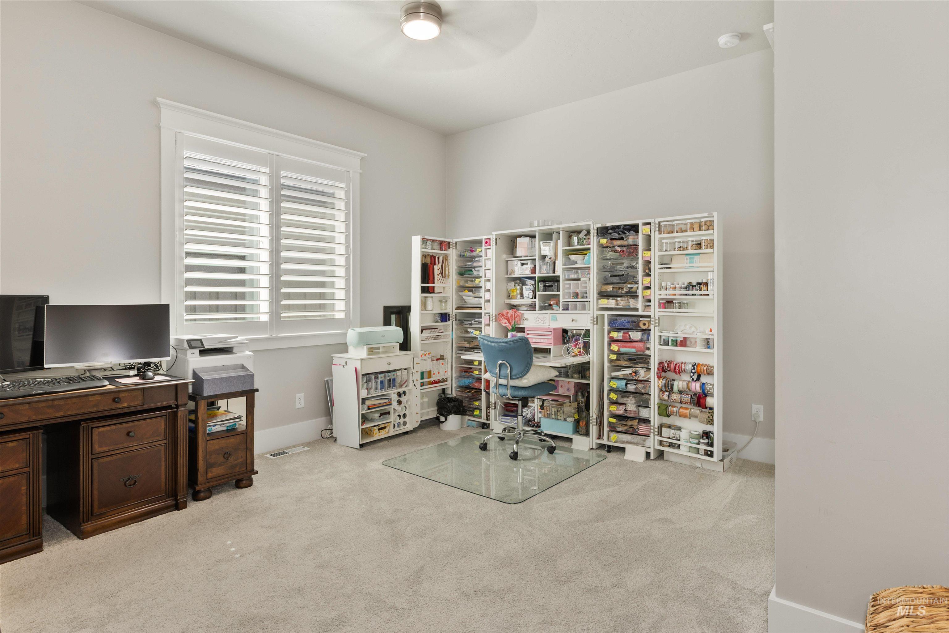 Office with light colored carpet and a ceiling fan