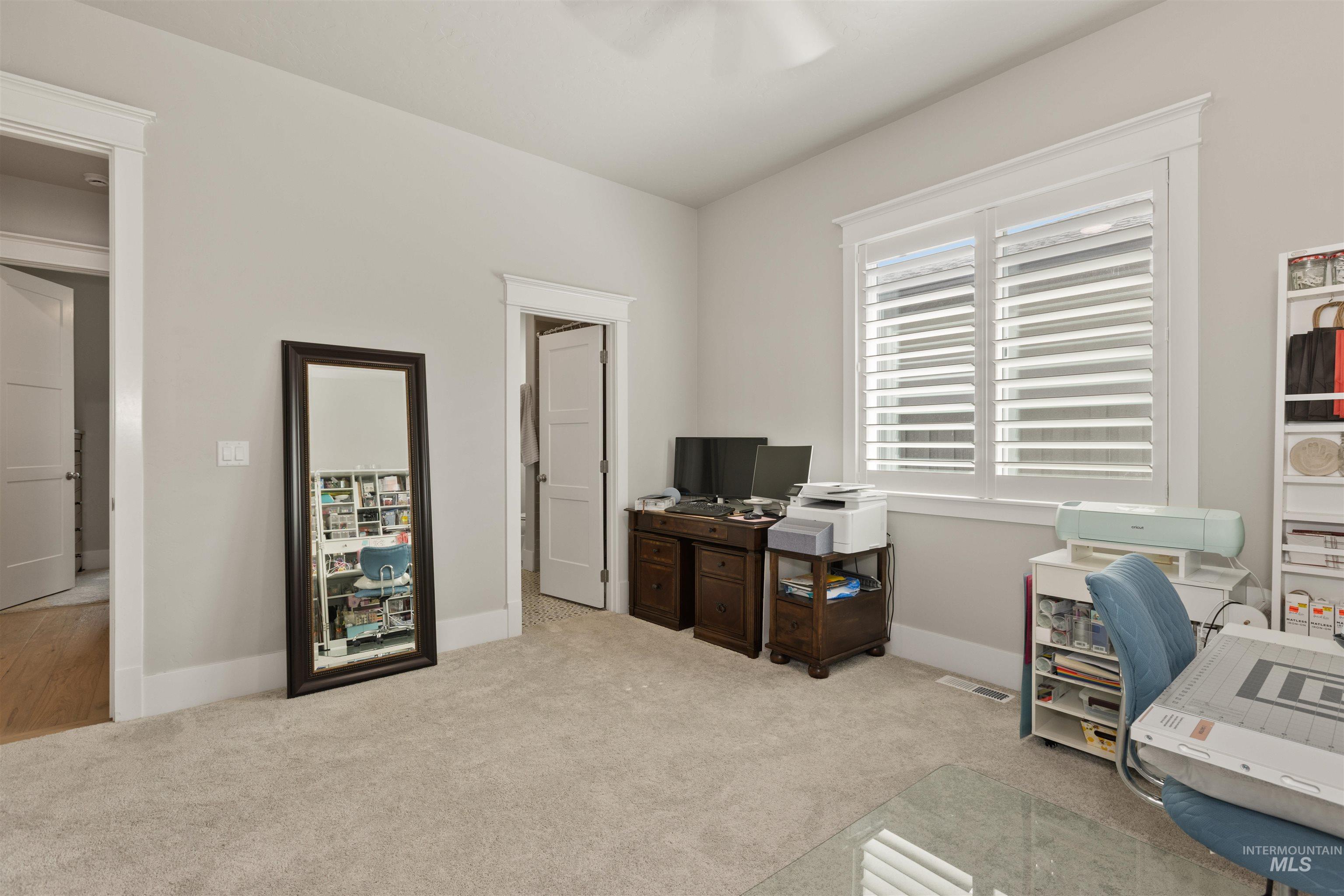 Home office featuring light carpet and a ceiling fan