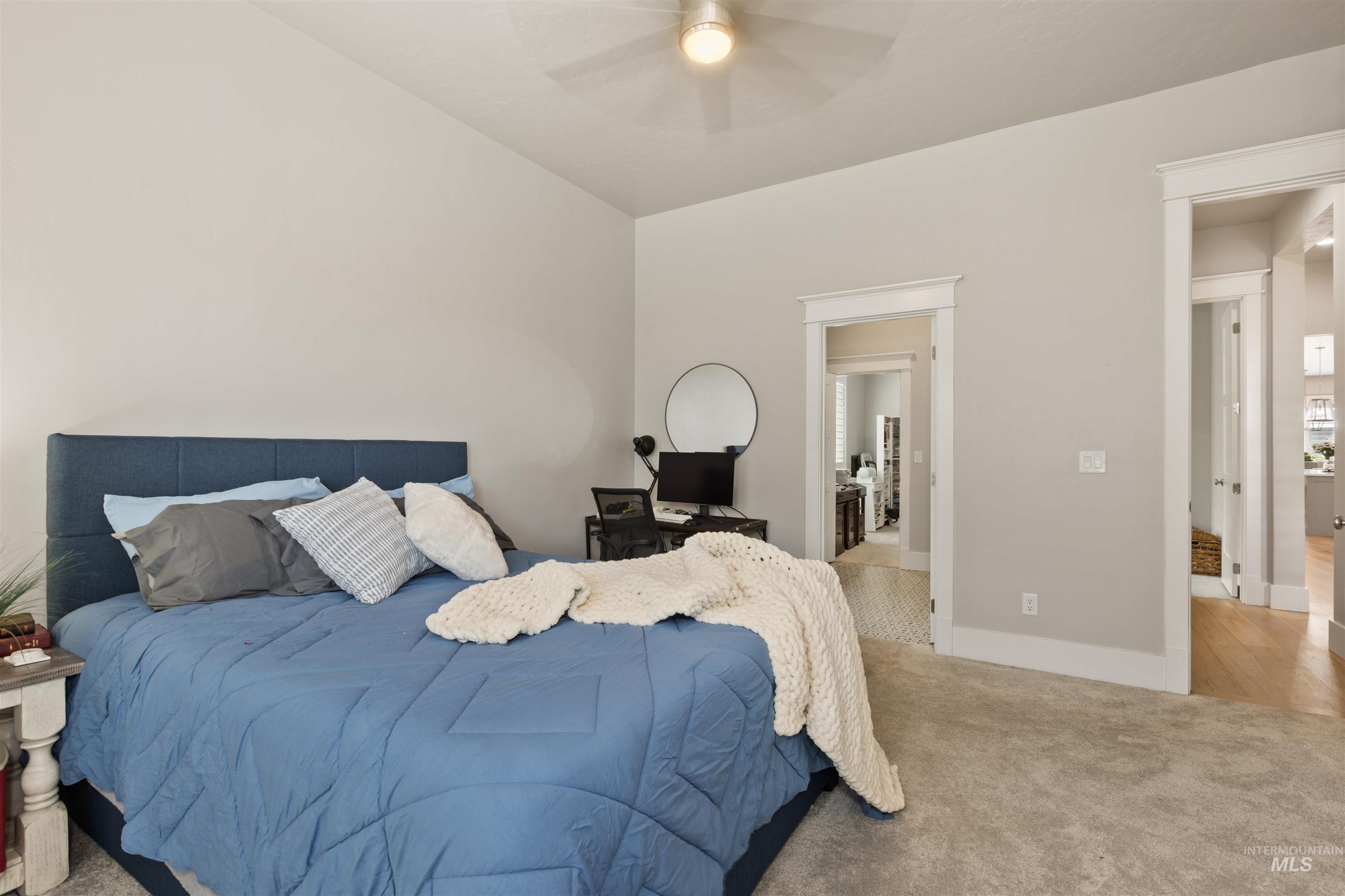 Carpeted bedroom featuring connected bathroom and ceiling fan