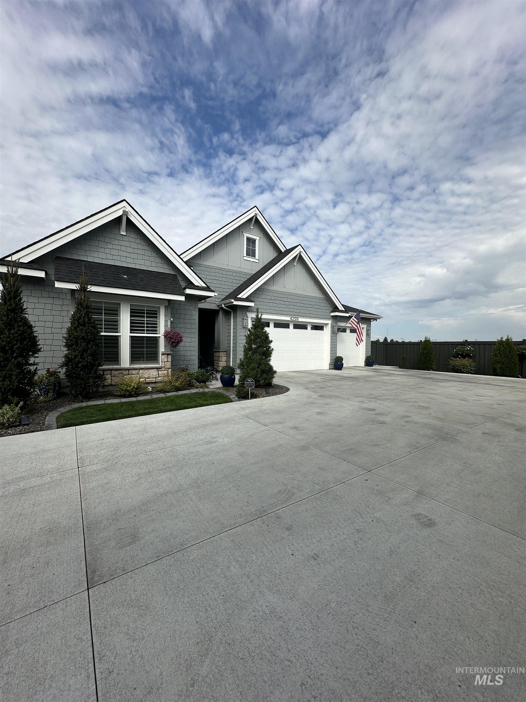 Craftsman-style home featuring driveway, stone siding, board and batten siding, and a garage