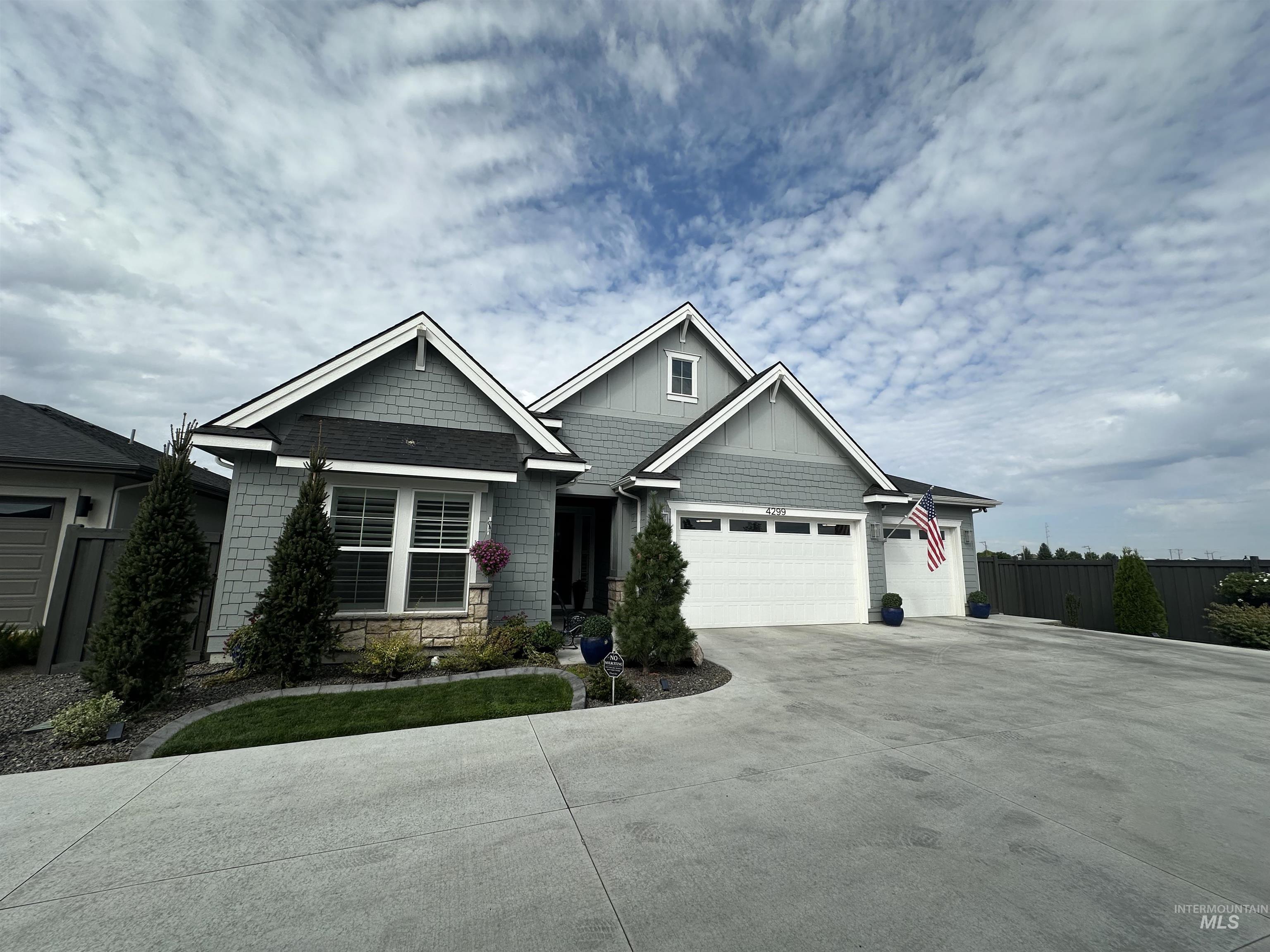 Craftsman-style home with driveway, stone siding, a garage, and board and batten siding