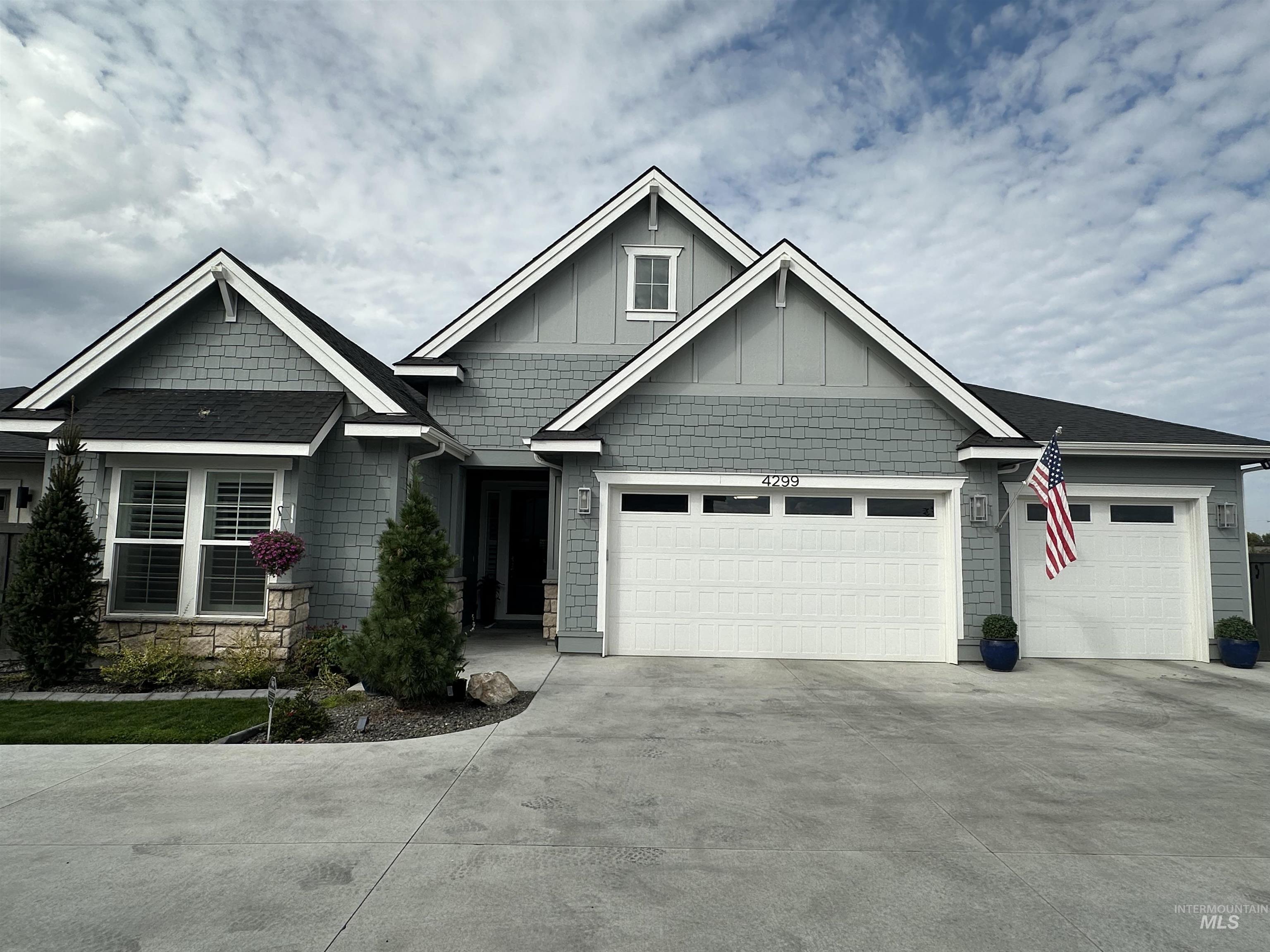 Craftsman house featuring driveway, stone siding, an attached garage, and board and batten siding