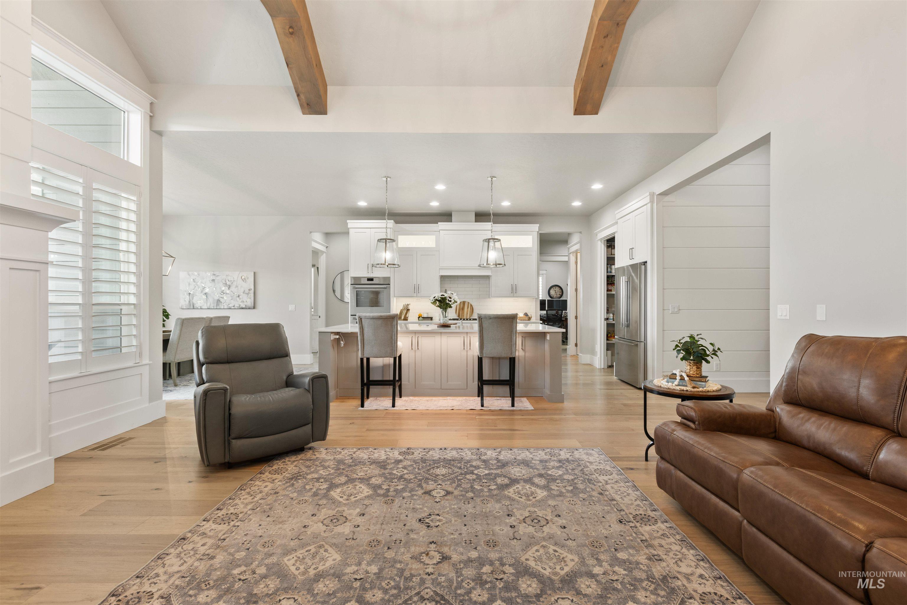 Living area with light wood finished floors, beam ceiling, and recessed lighting