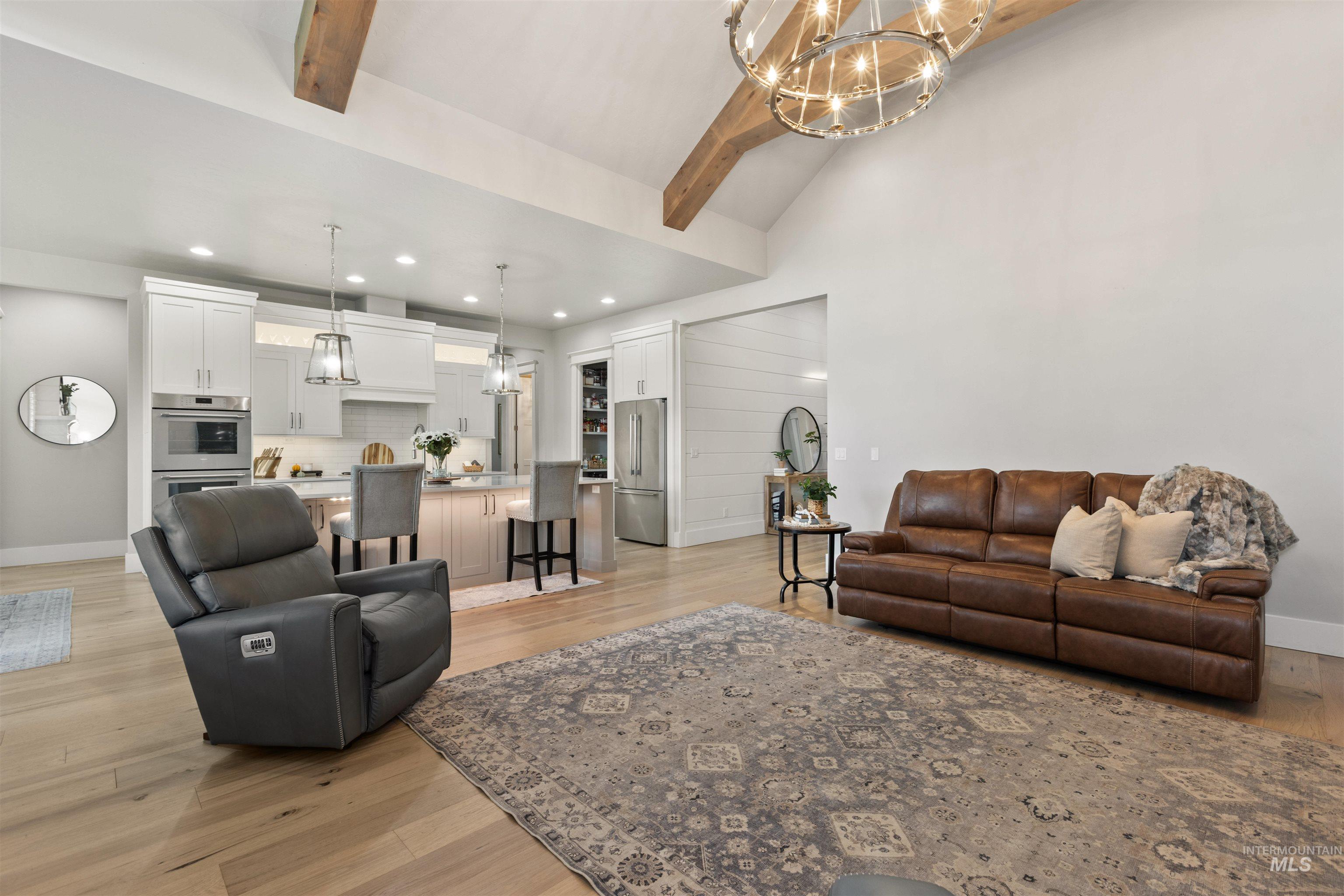Living area featuring a chandelier, light wood finished floors, beamed ceiling, high vaulted ceiling, and recessed lighting