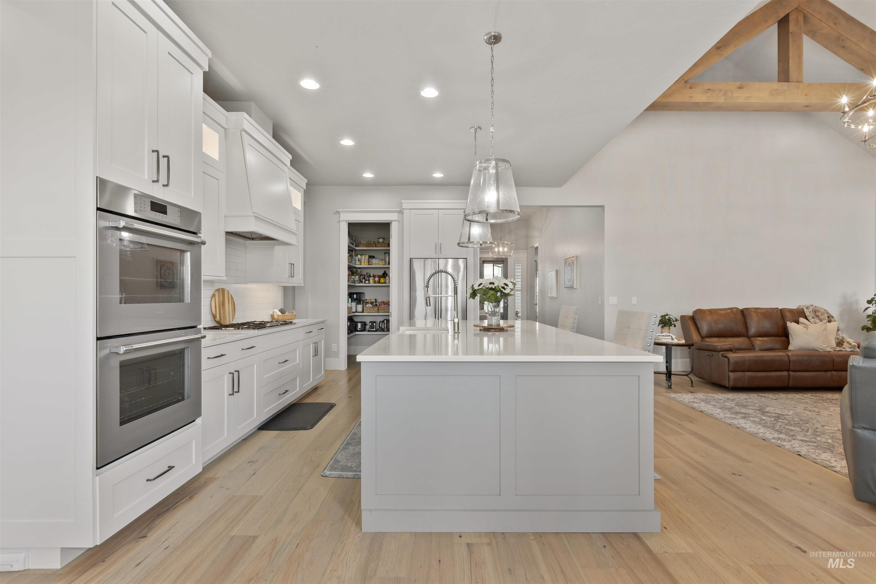 Kitchen featuring stainless steel appliances, beamed ceiling, open floor plan, hanging light fixtures, and recessed lighting