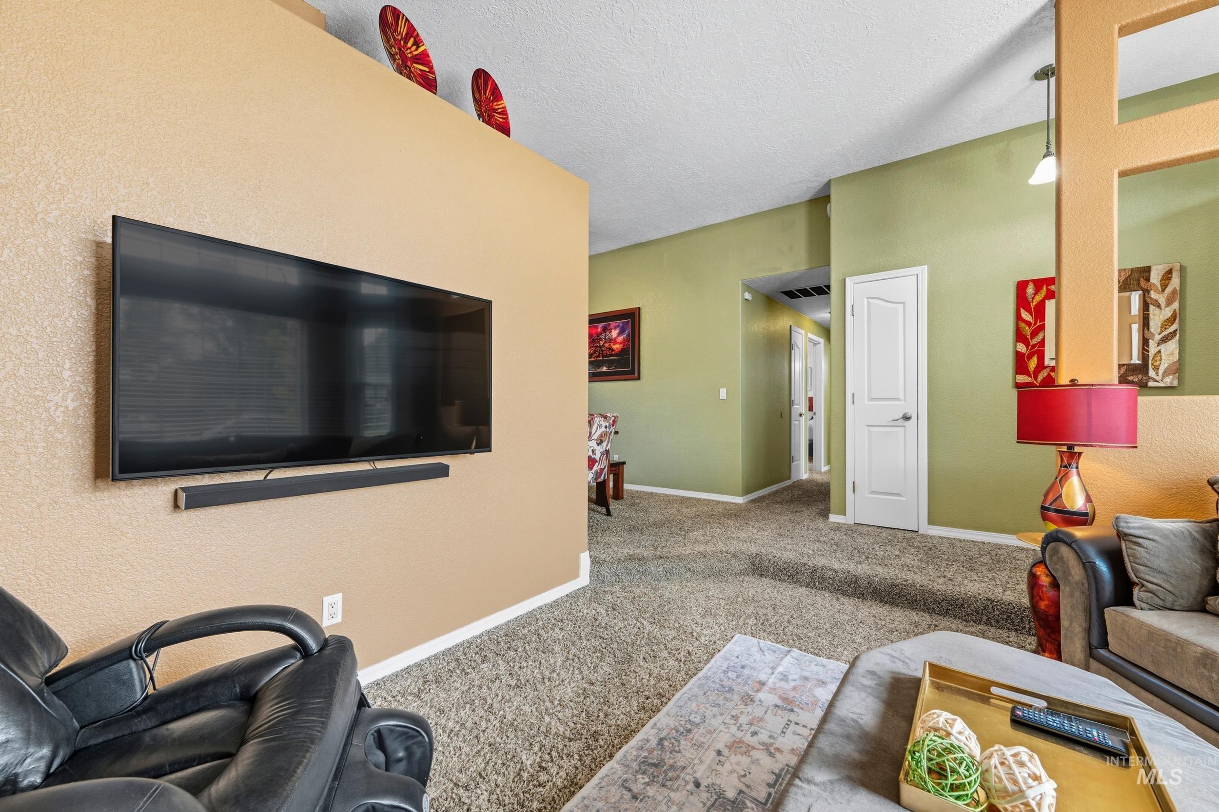 Living room with a textured ceiling, carpet floors, and a textured wall