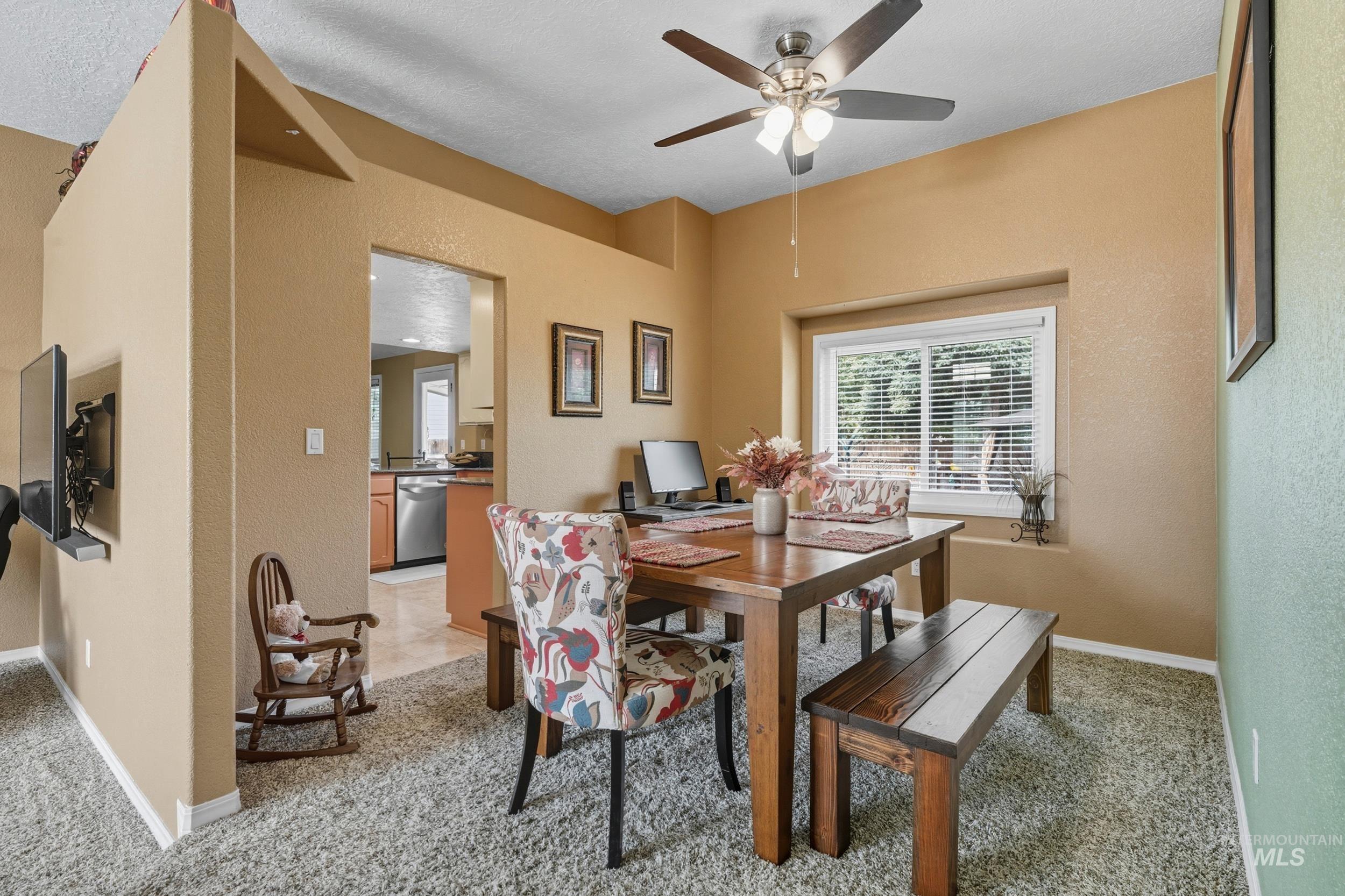 Dining area featuring a textured wall, light colored carpet, and ceiling fan