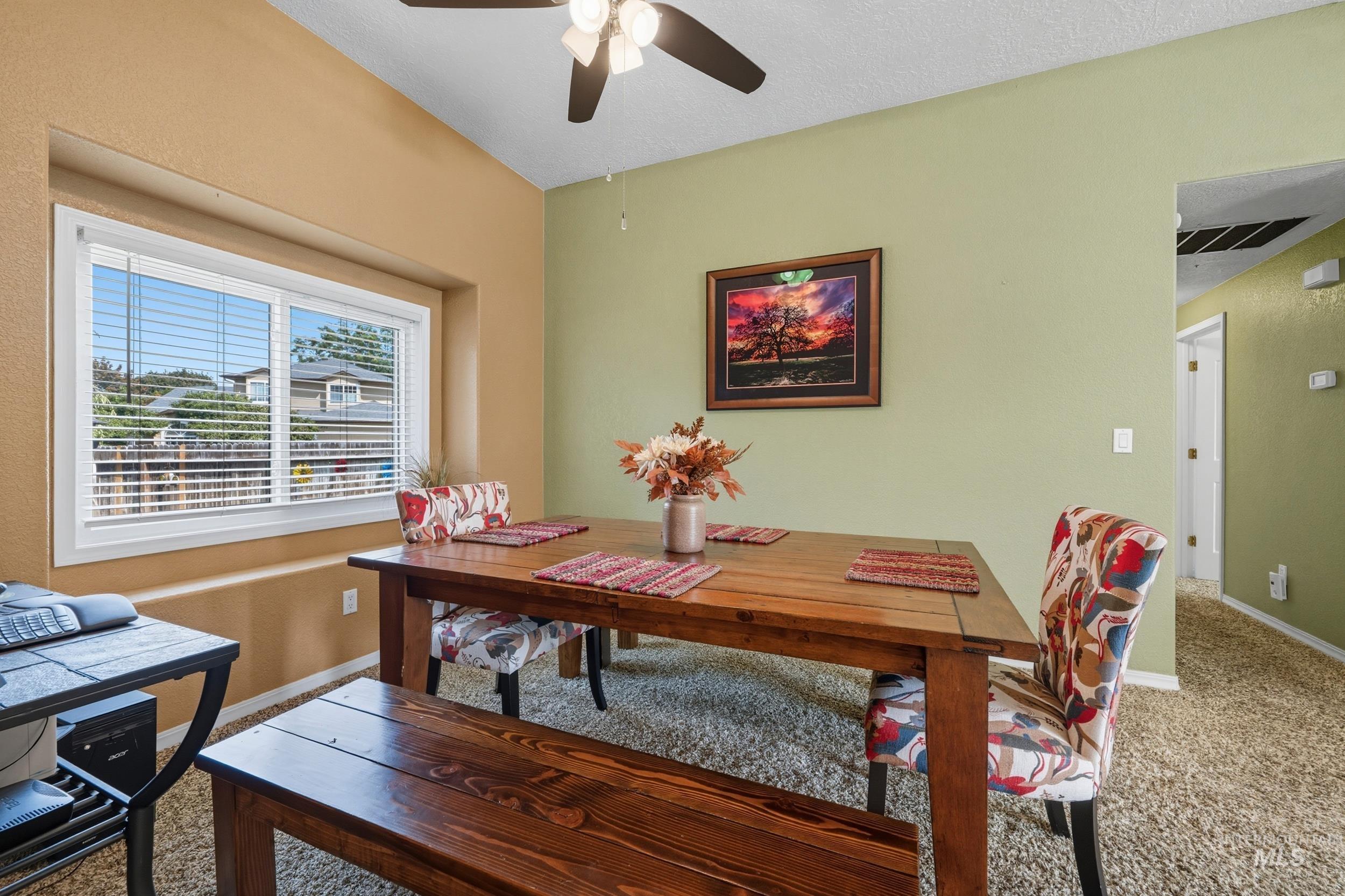 Carpeted dining area featuring ceiling fan and a textured ceiling