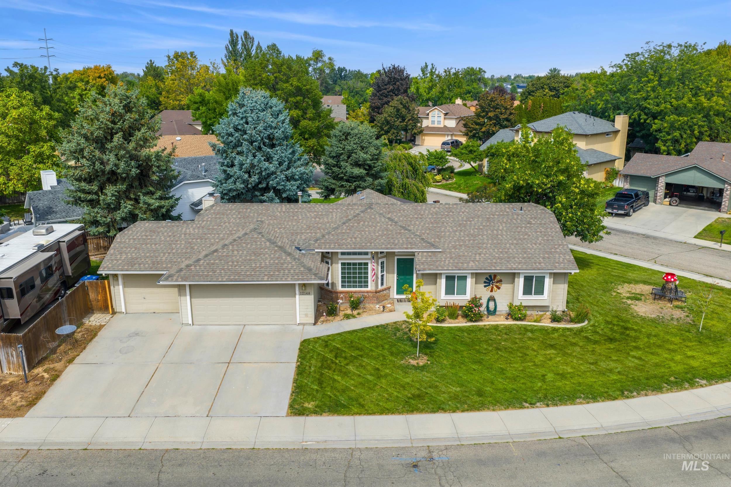 Ranch-style home featuring an attached garage, a front yard, driveway, and a residential view