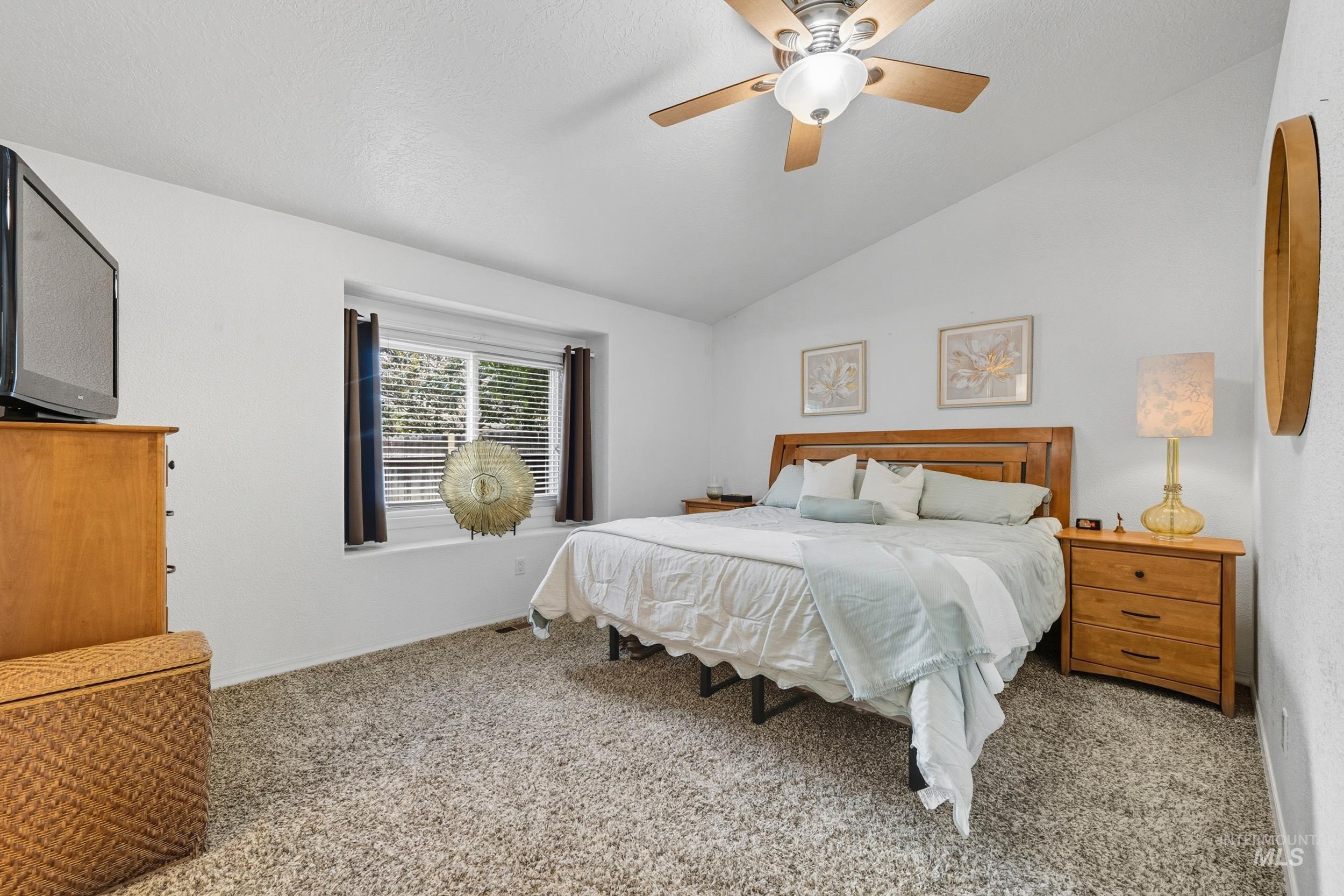 Bedroom with vaulted ceiling, light colored carpet, and a ceiling fan