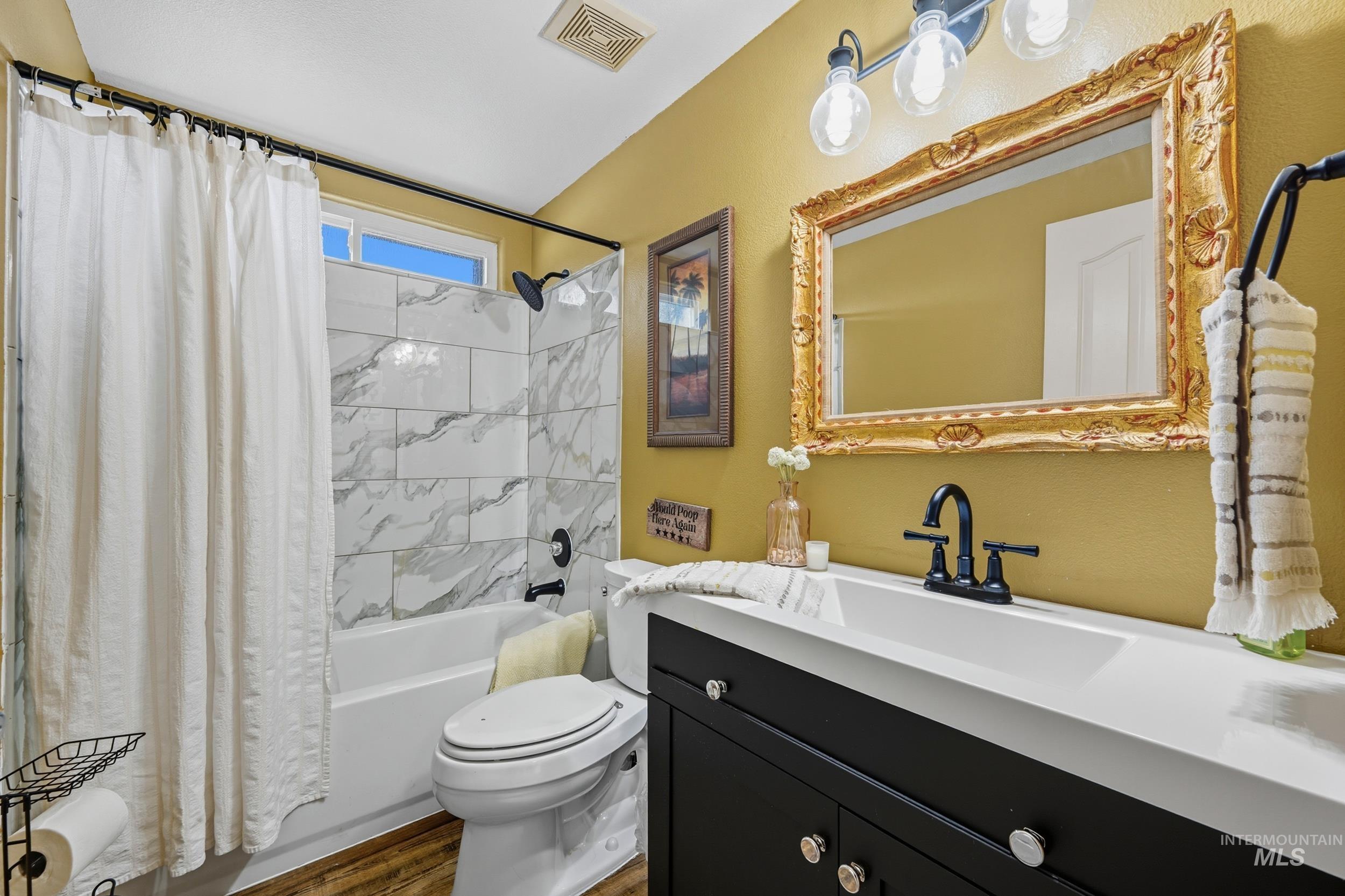Bathroom with shower / bath combo with shower curtain, vanity, and dark wood finished floors