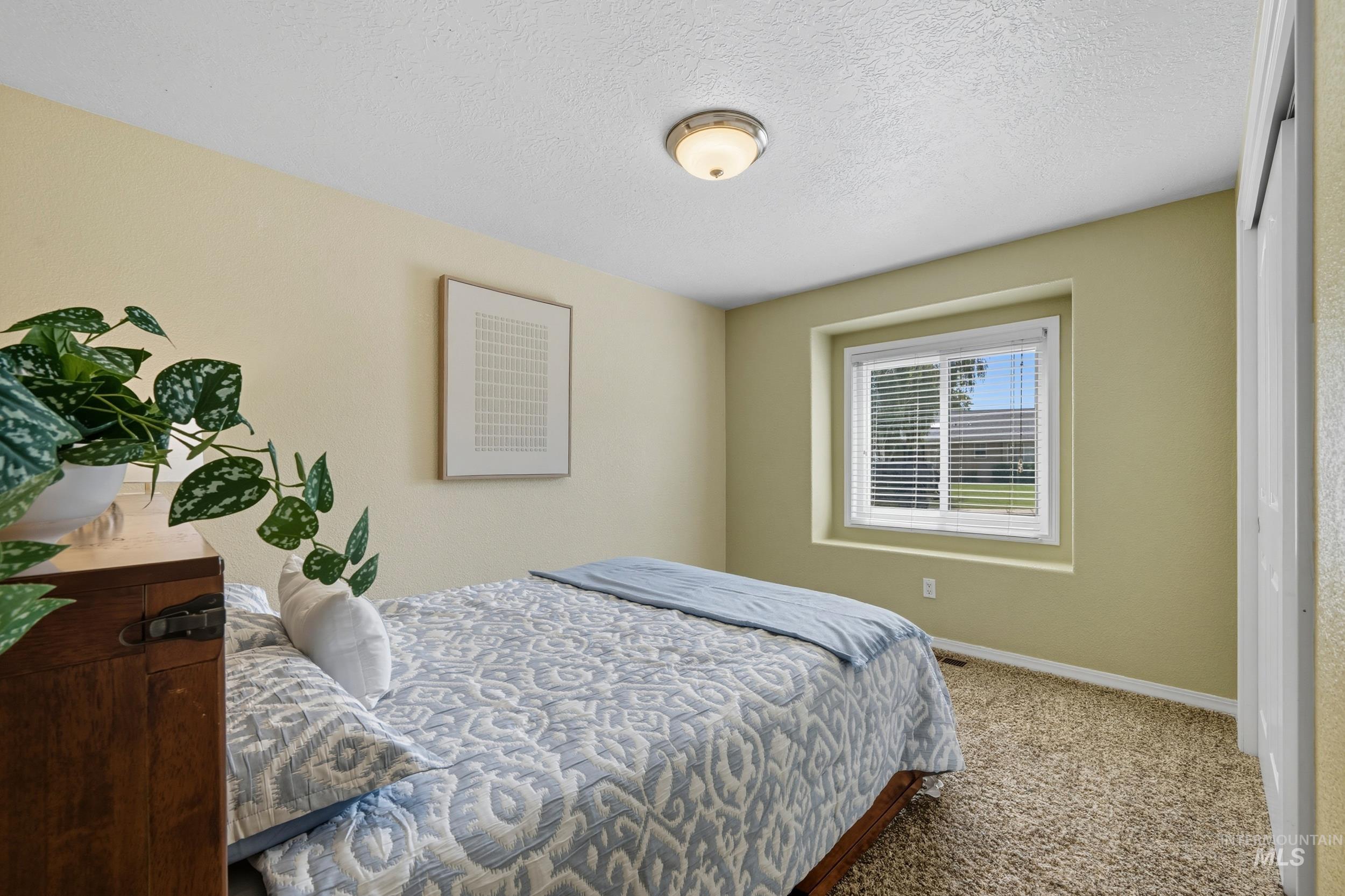 Carpeted bedroom featuring a textured ceiling and baseboards
